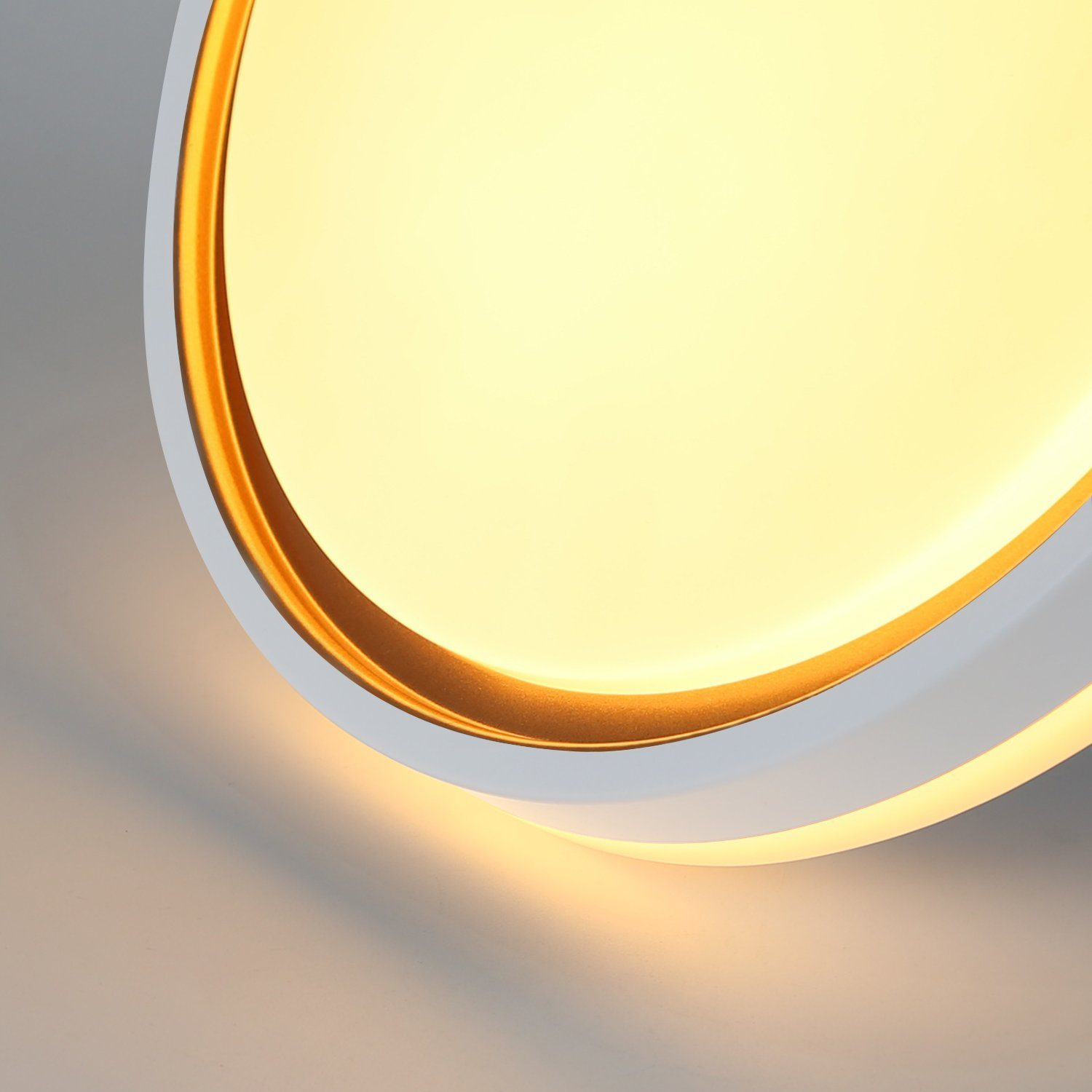 Nahaufnahme einer Deckenleuchte. Sie hat einen weißen Ring und einen goldenen Innenring, der warmes Licht abgibt.