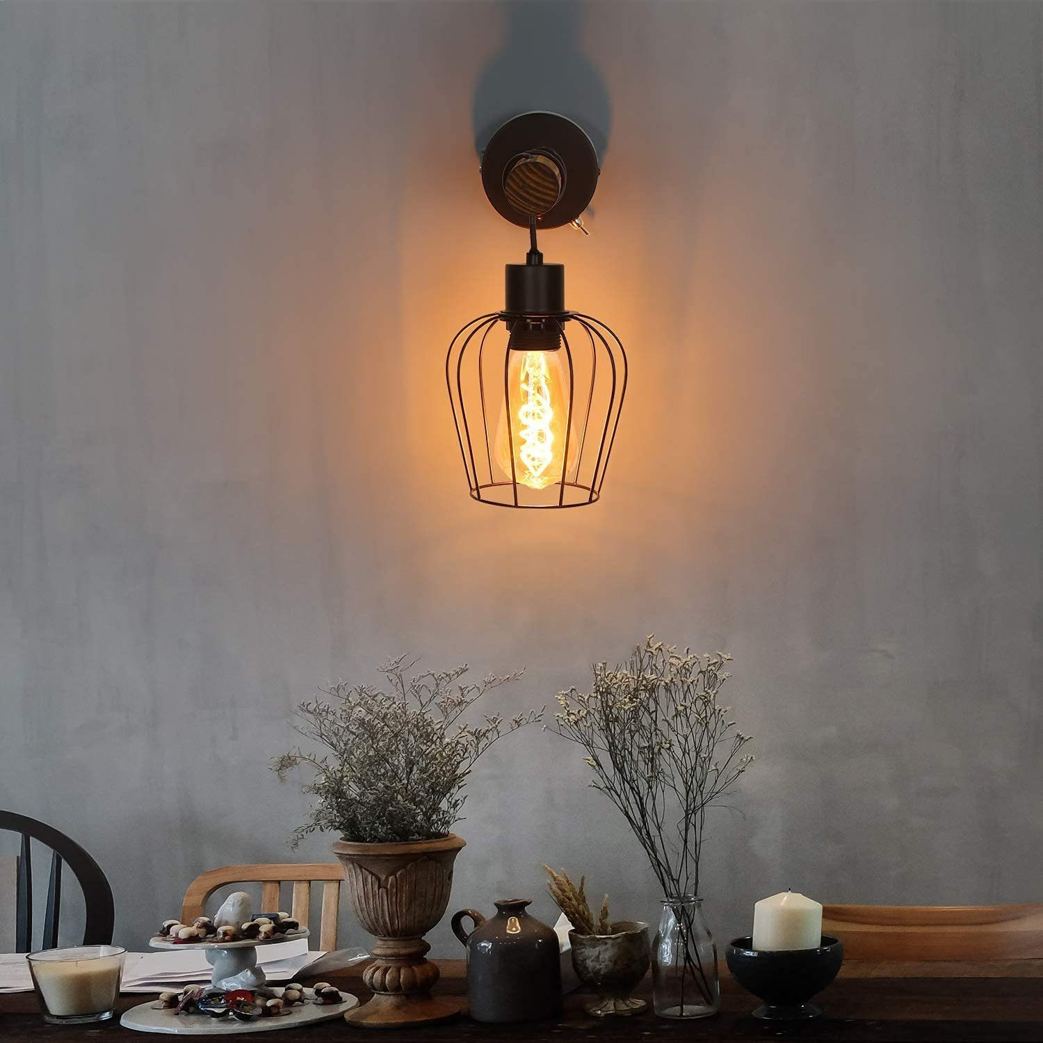 Un lampadario in stile vintage appeso sopra un tavolo con decorazioni. Il tavolo ha oggetti decorativi e una candela.