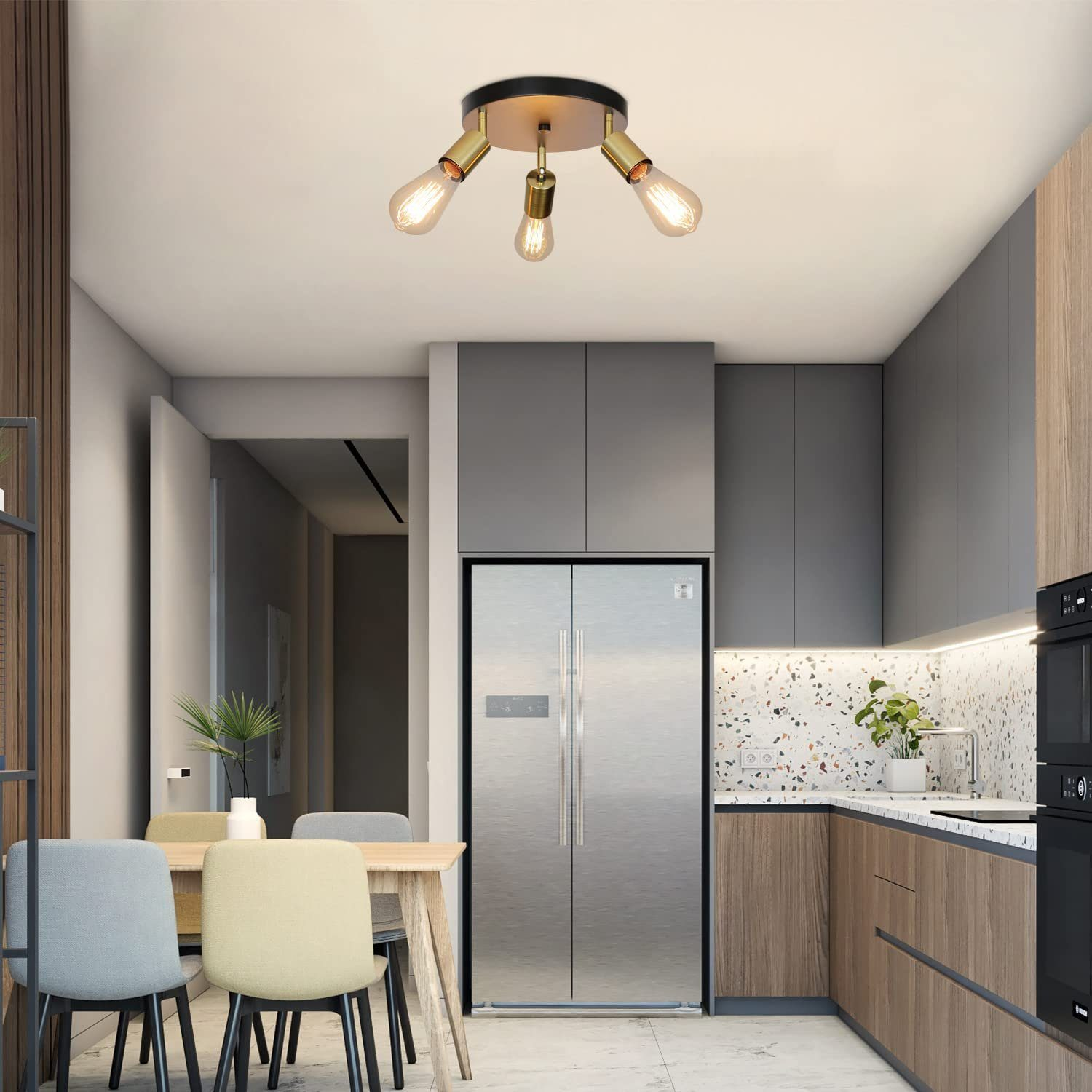Cucina con un lampadario a soffitto con tre lampadine. La stanza ha un frigorifero e un tavolo da pranzo.
