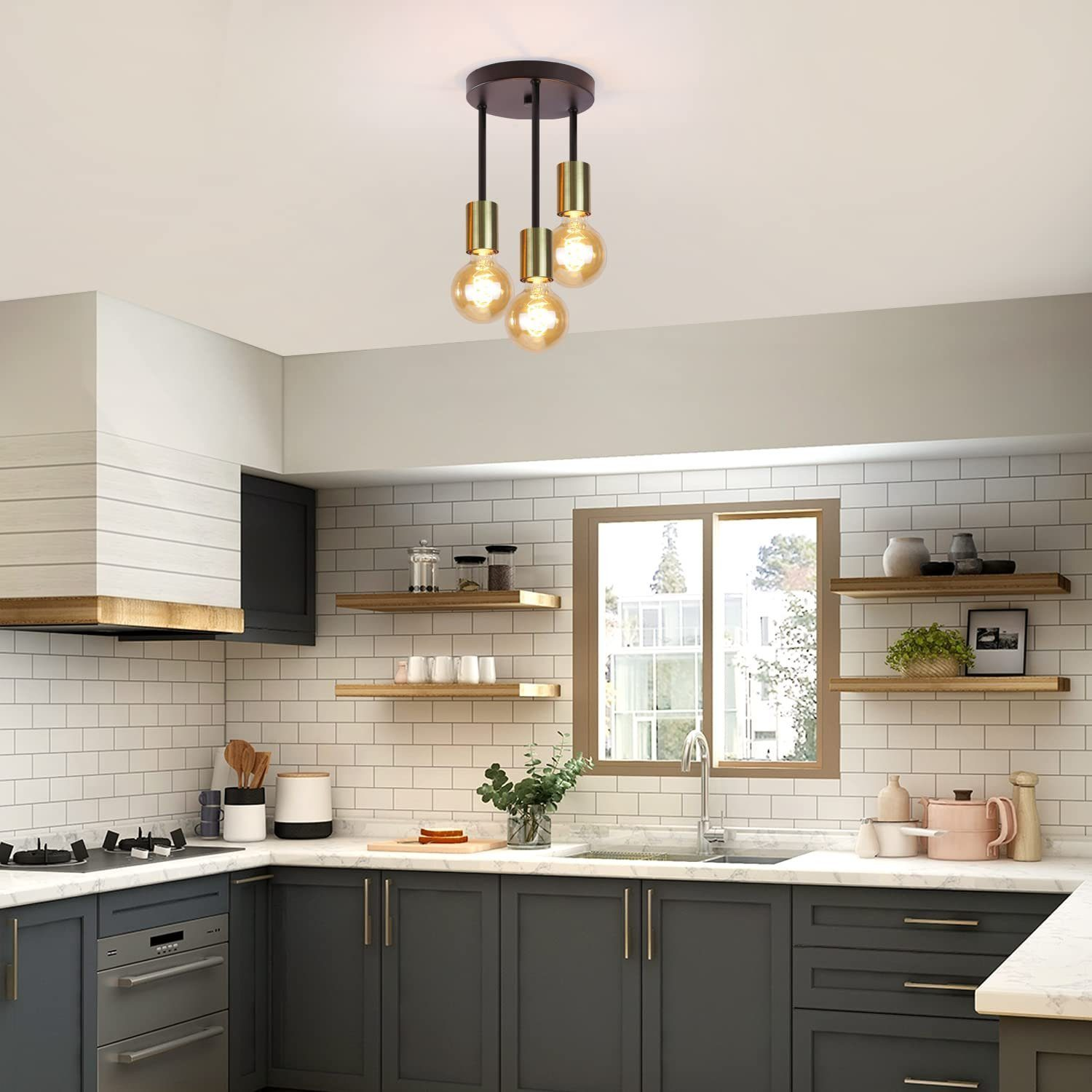 Una cucina con un lampadario a soffitto con tre lampadine. Ci sono armadi e mensole.