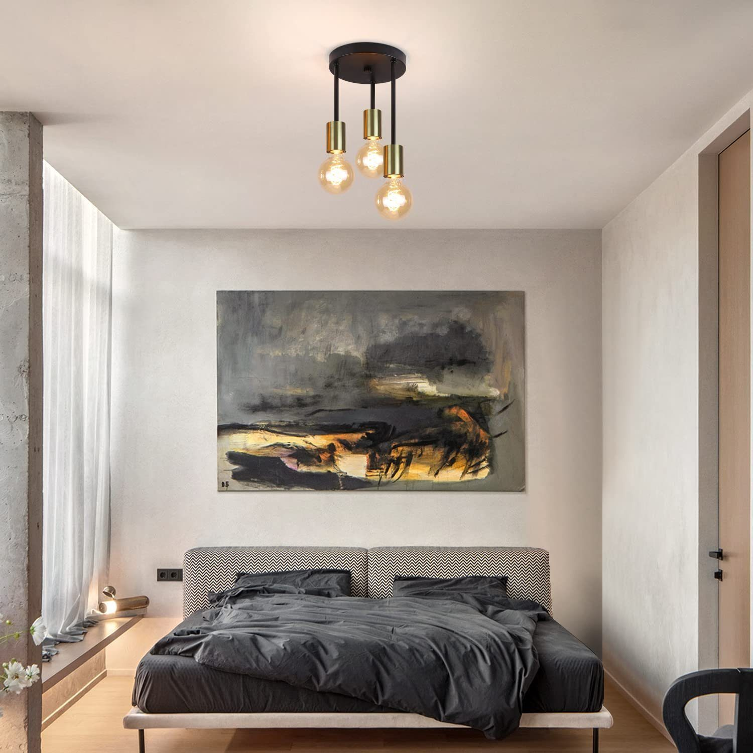 Scena di camera da letto con tre lampade a sospensione, letto e grande dipinto astratto.
