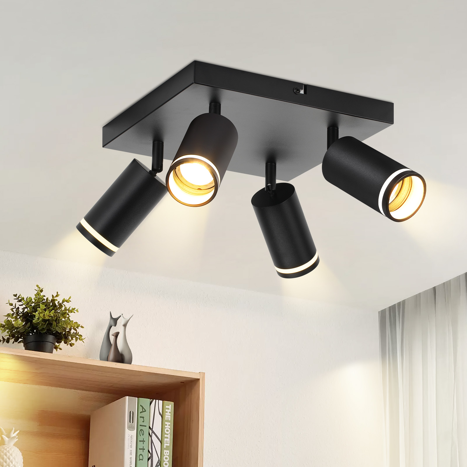 Faretto da soffitto nero con quattro luci regolabili. In primo piano una mensola con decorazioni.