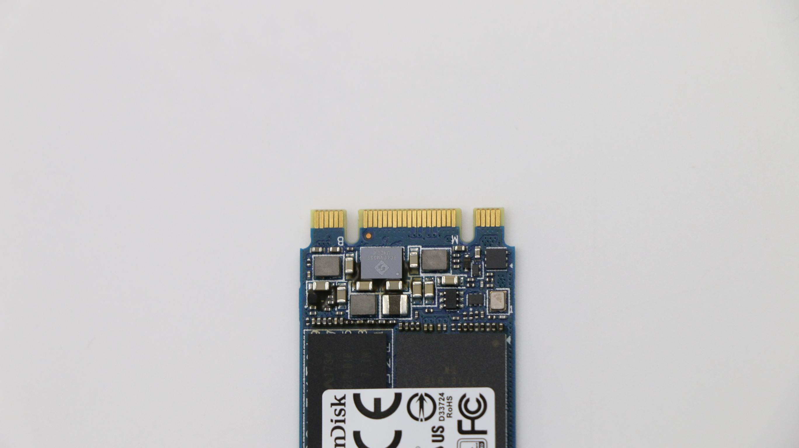 Composant électronique, un SSD Sandisk, sur fond blanc. Il comporte diverses puces et connecteurs dorés.