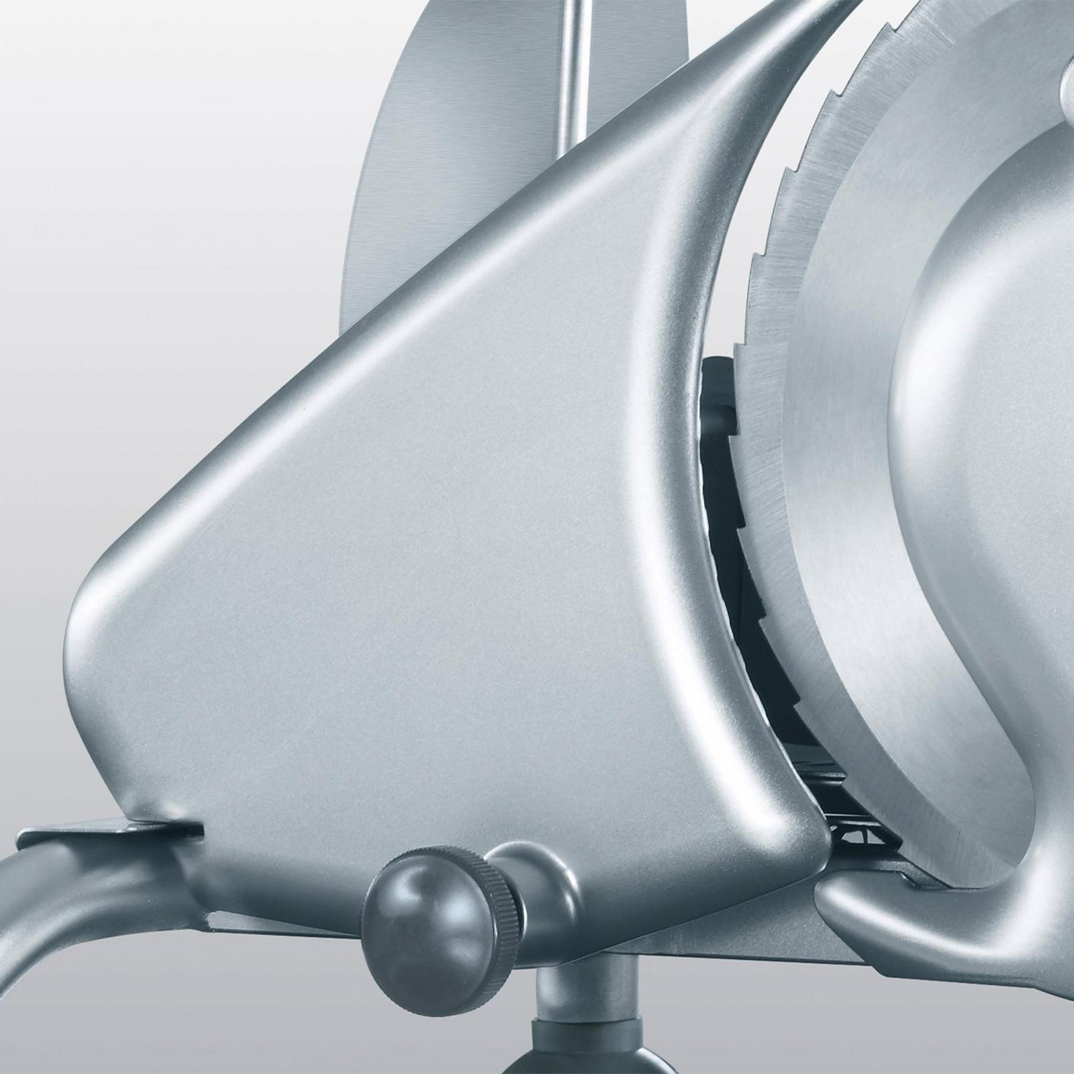 Srebrna krajalnica z ząbkowanym ostrzem. Ma pokrętło i zakrzywiony korpus.