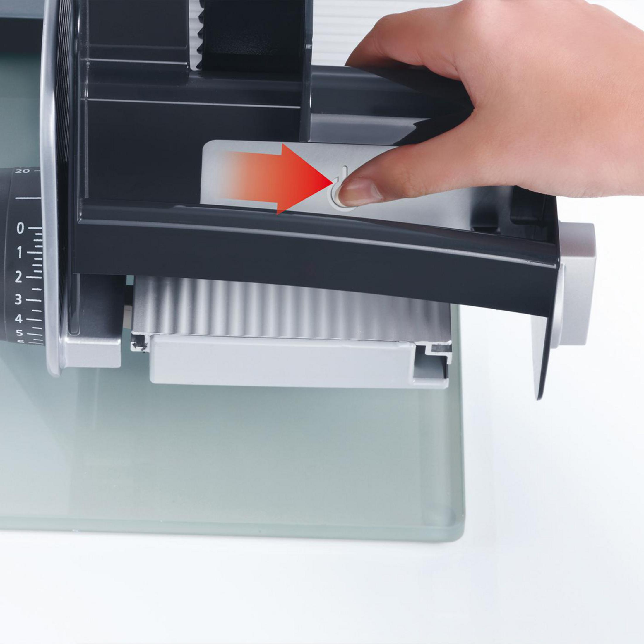 Ręka naciskająca przycisk na czarno-szarej krajalnicy.