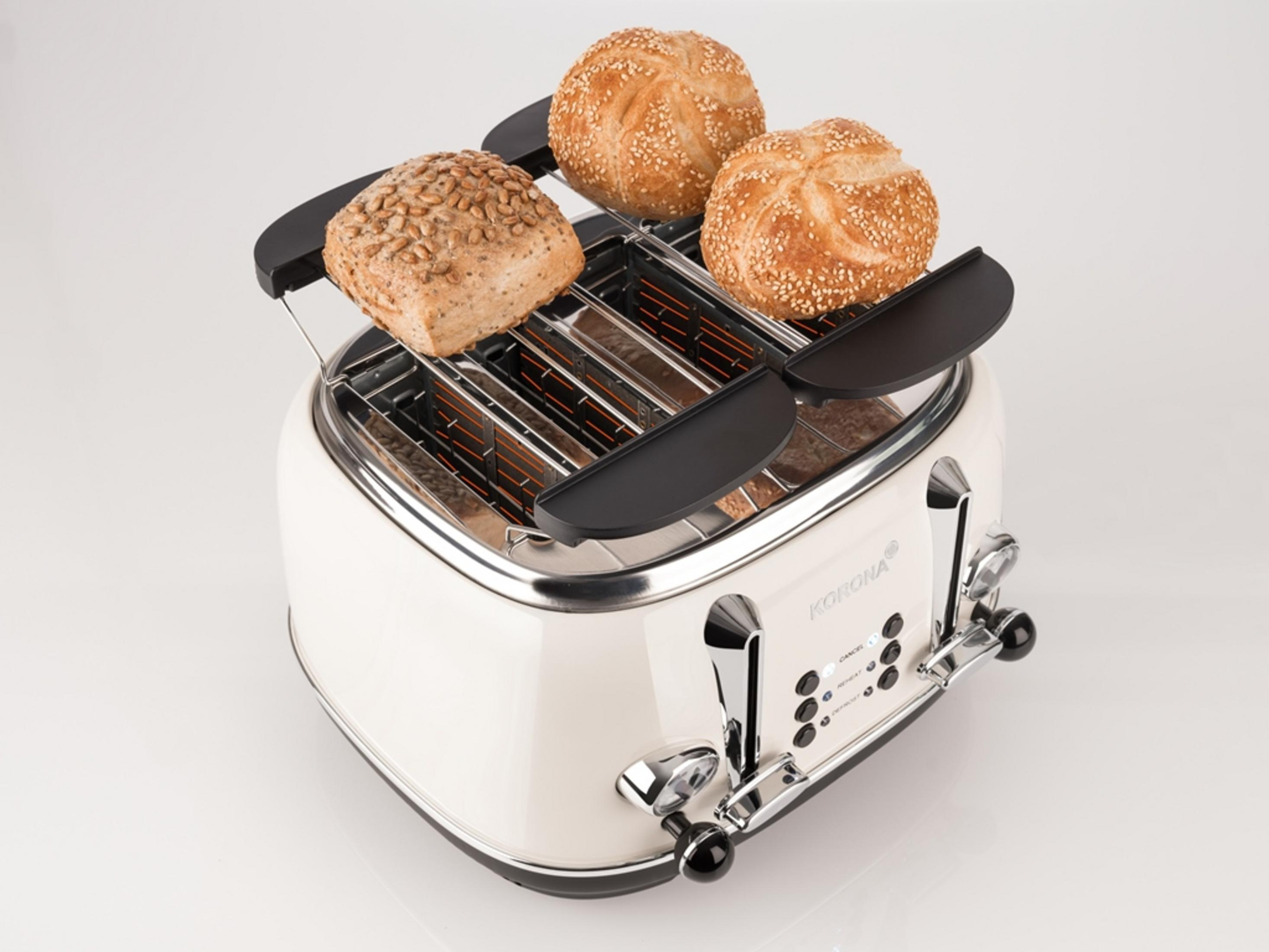 Kremowy toster z bułkami. Toster ma cztery szczeliny. Dwie bułki na wierzchu.