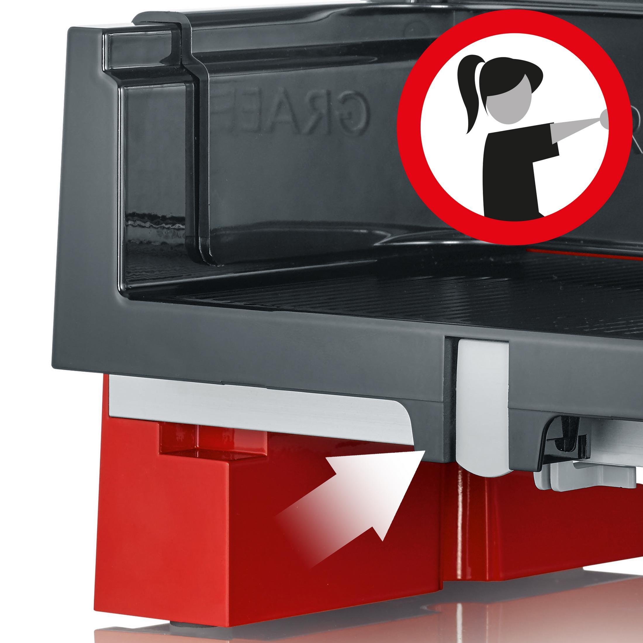 Zbliżenie krajalnicy ze znakiem ostrzegawczym i czerwoną tacą. Strzałka wskazuje kierunek tacy.