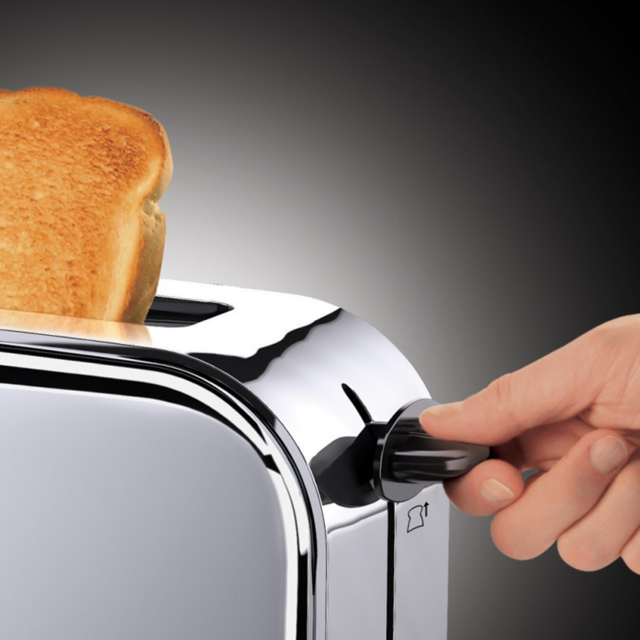 Hand dreht einen Drehregler an einem Chrom-Toaster, mit Brot darin.