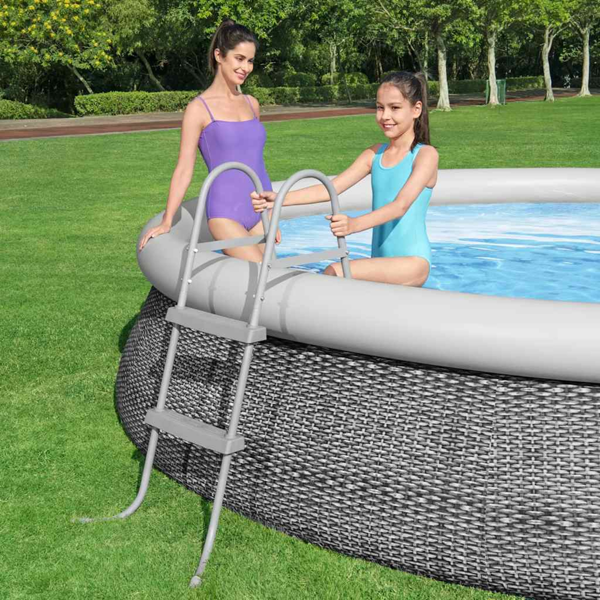 Zwei Frauen in Badeanzügen in der Nähe eines Pools mit einer Leiter auf einer Rasenfläche.