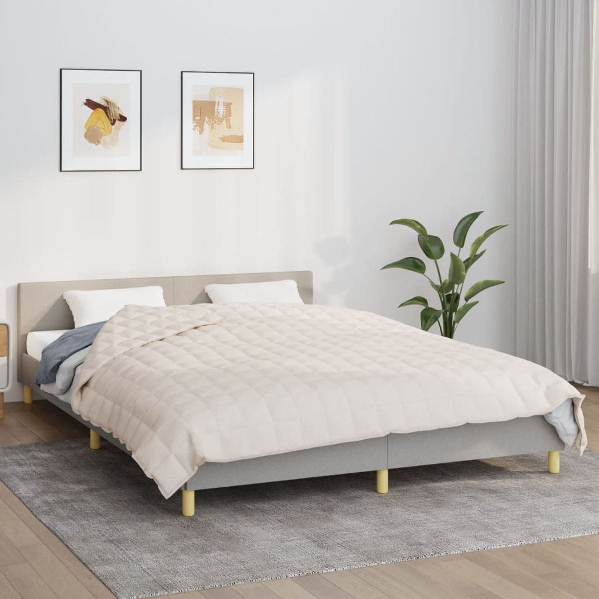 Ein Bett mit Steppdecke, Kissen und zwei Bildern an der Wand, auf einem grauen Teppich.