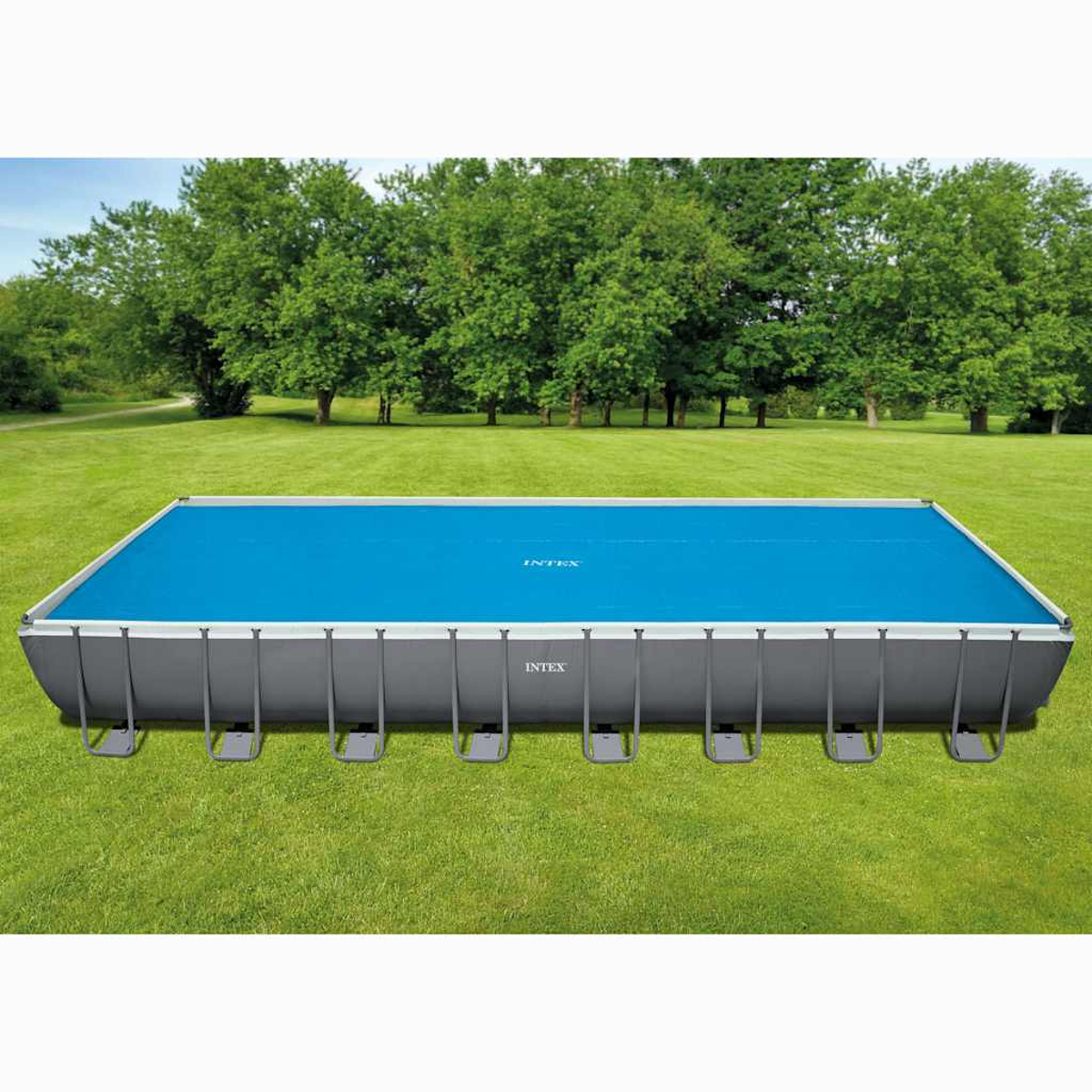 Ein rechteckiger oberirdischer Pool mit blauer Abdeckung auf grünem Gras.