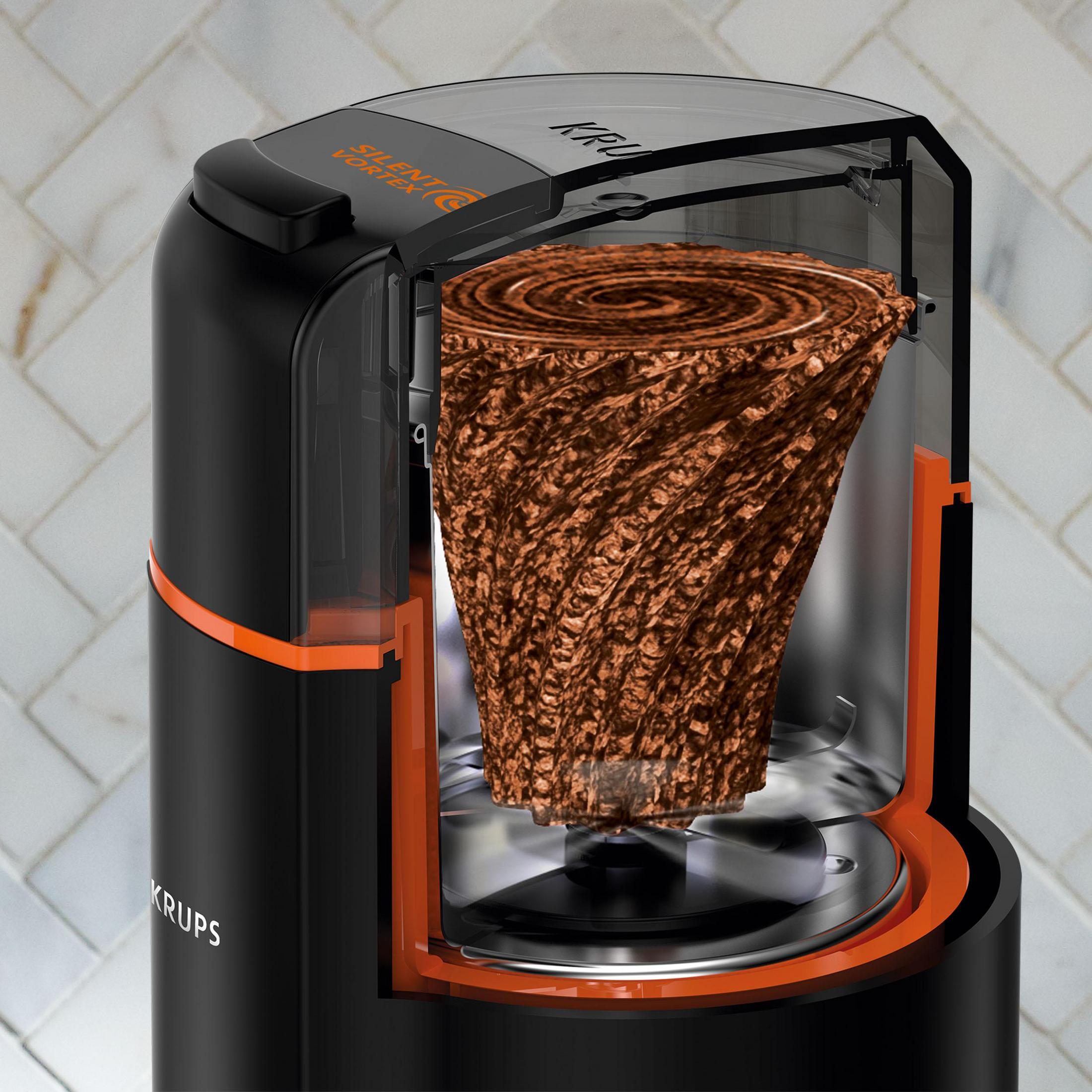 Czarny i pomarańczowy młynek do kawy Krups, pokazujący zmieloną kawę w środku.