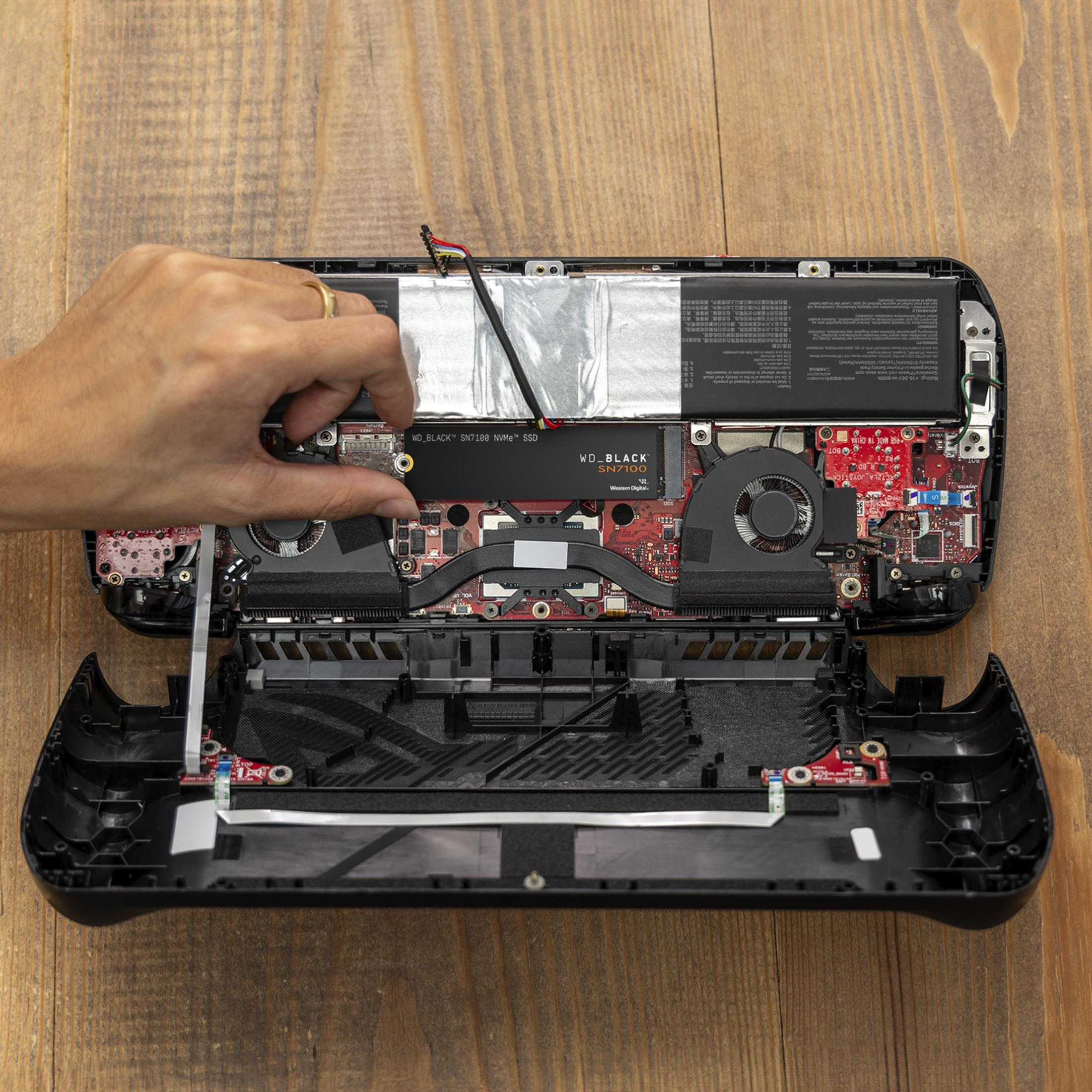 Mano che installa un SSD NVMe WD_BLACK SN7100 in un dispositivo, con componenti.