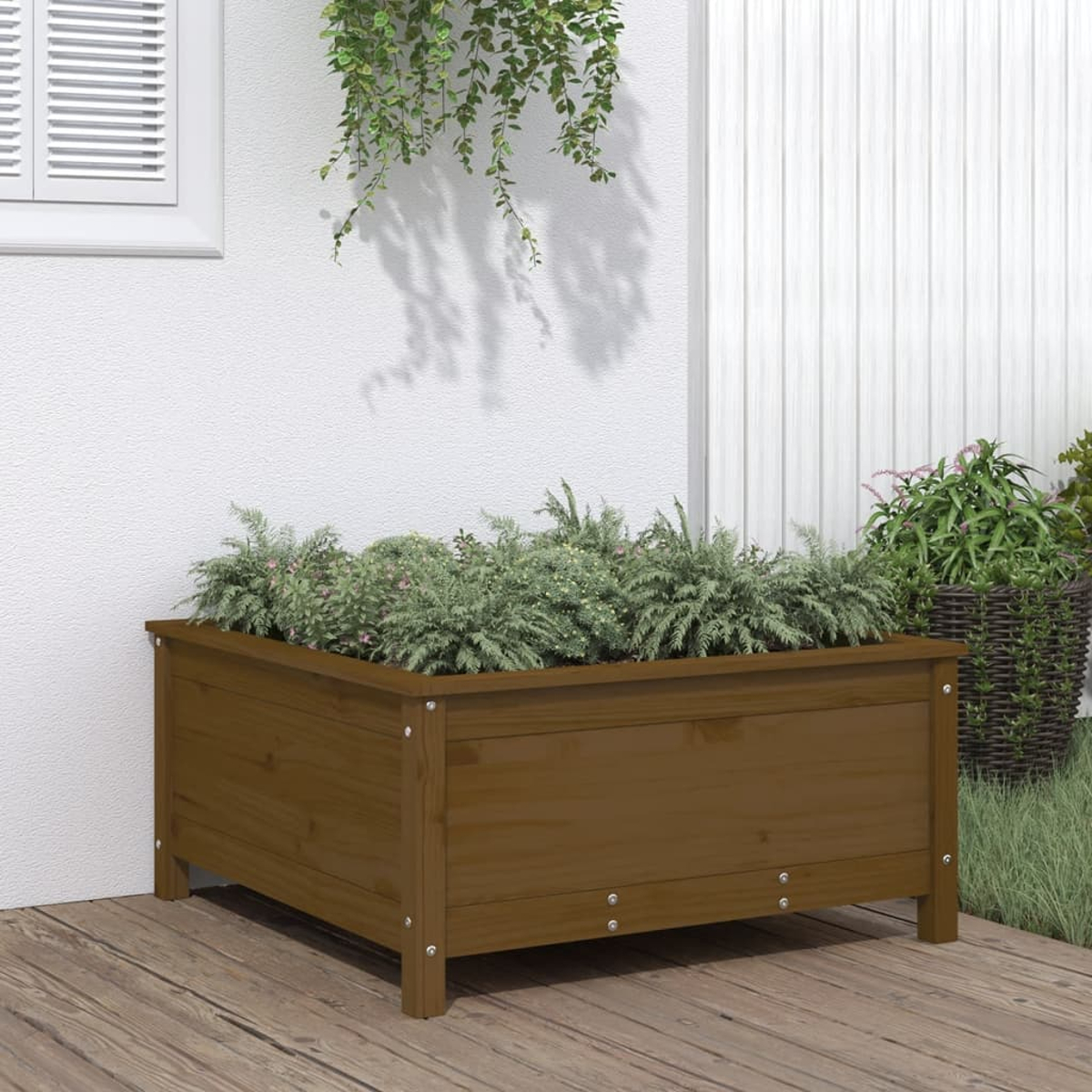 Braune Holz-Pflanzkiste, gefüllt mit grünen Pflanzen, auf Holzterrasse.