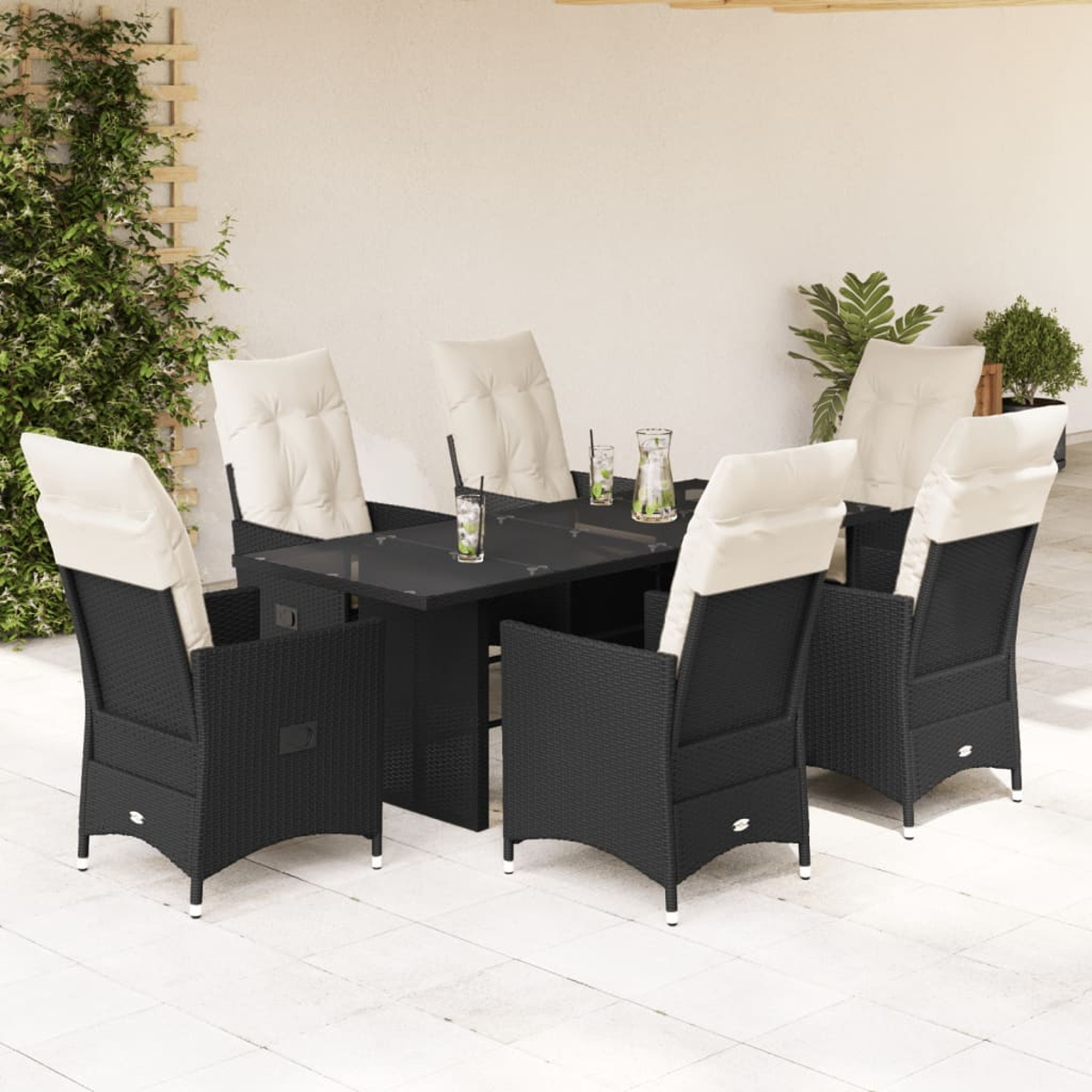 Ein Terrassenset mit schwarzem Tisch, Stühlen und weißen Kissen. Weißer Terrassenboden, grüner Hintergrund.