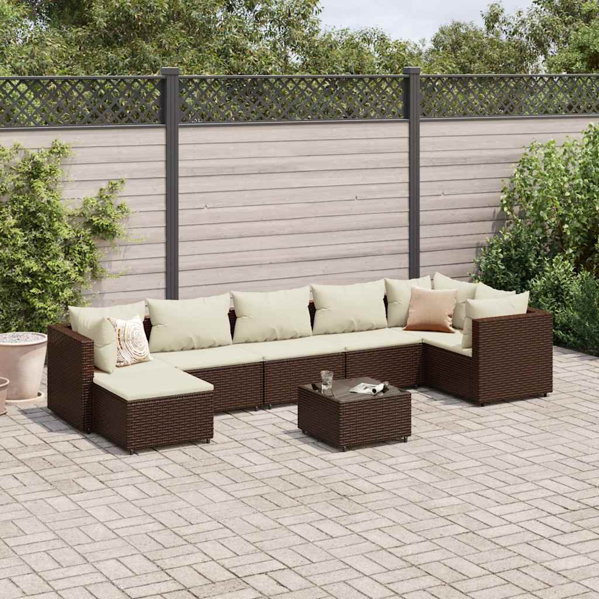 Brauner Outdoor-Schnitt aus Korbgeflecht mit beigen Kissen und einem Couchtisch auf einer Terrasse.