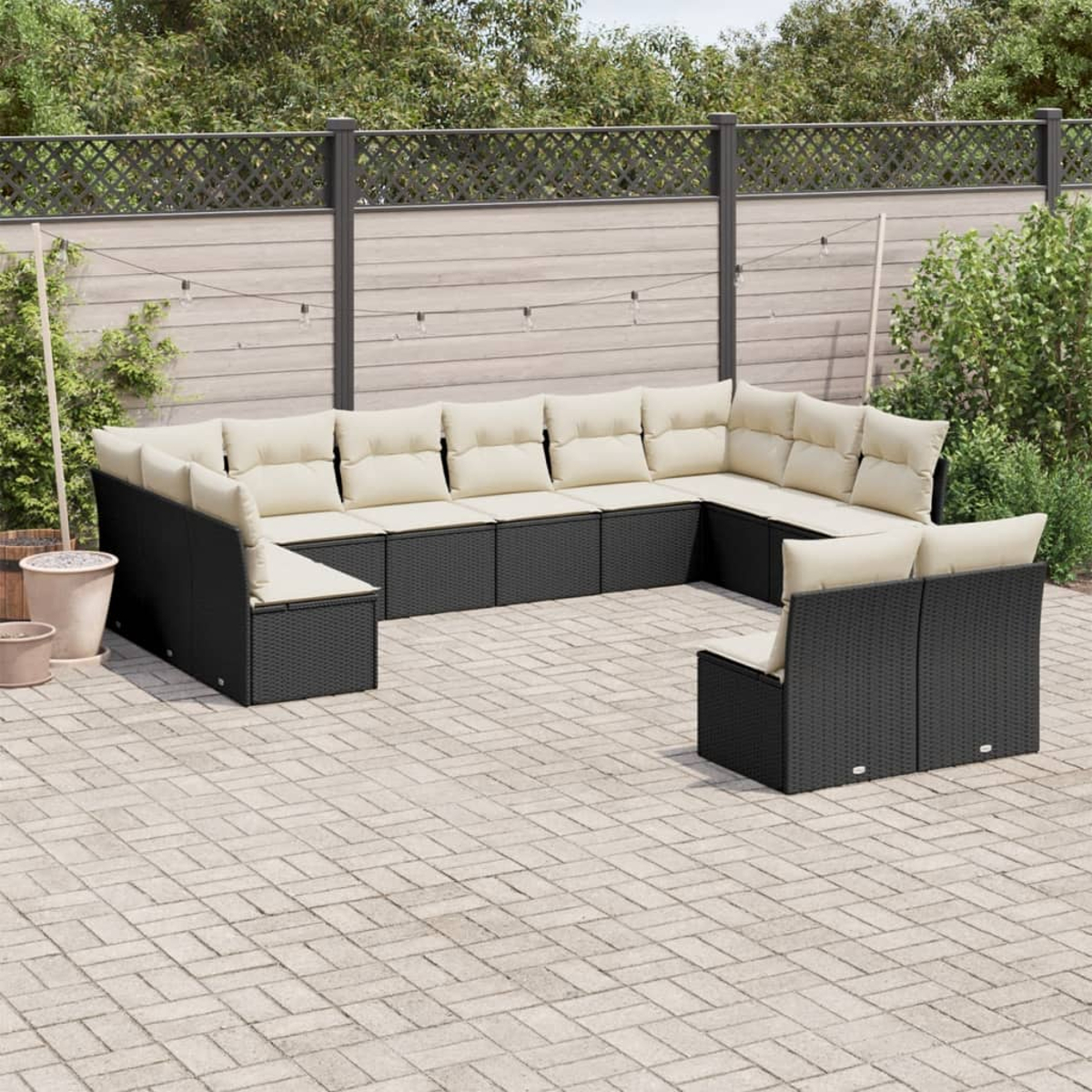 Schwarzes Korbsitzgruppen-Set mit beigen Kissen. Auf einer Terrasse platziert.