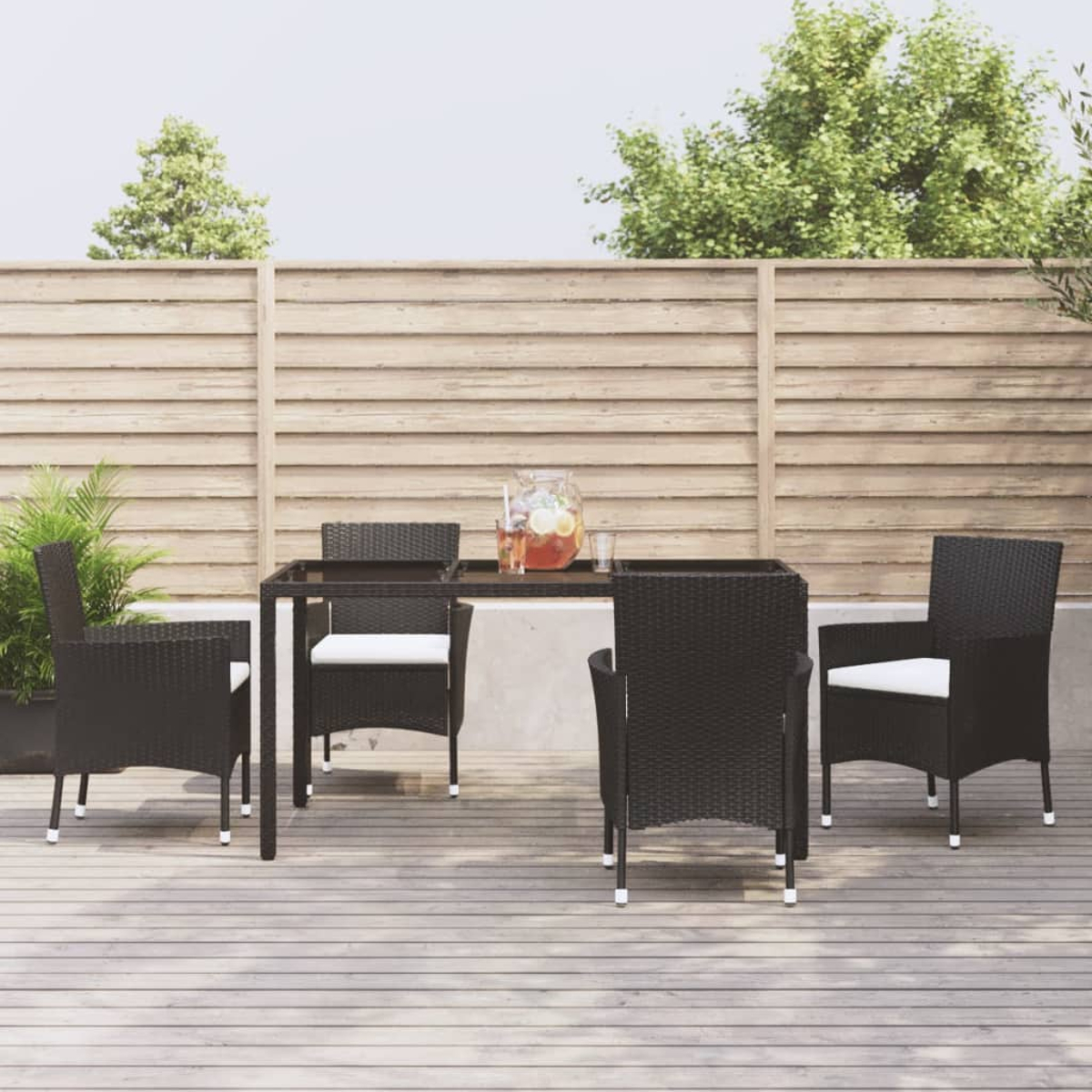 Terrassenset: schwarze Stühle, weiße Kissen, Glastisch und Holzzaun im Hintergrund.