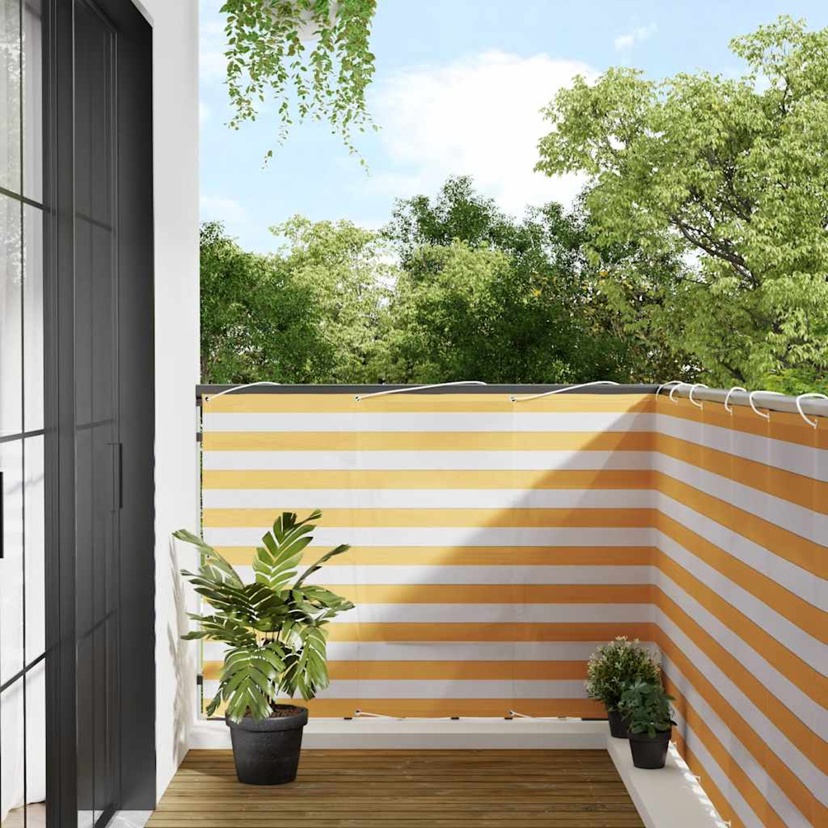 Un balcone con schermo per la privacy a righe gialle e bianche, piante e pavimento in legno.