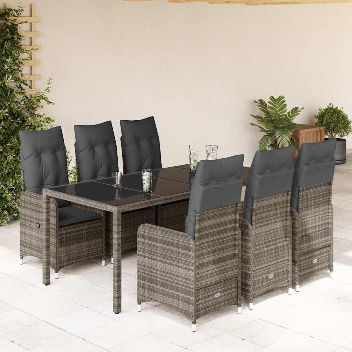 Essgruppe für den Außenbereich. Rattan-Tisch und -Stühle mit grauen Kissen. Im Hintergrund sind Terrasse und Pflanzen zu sehen.