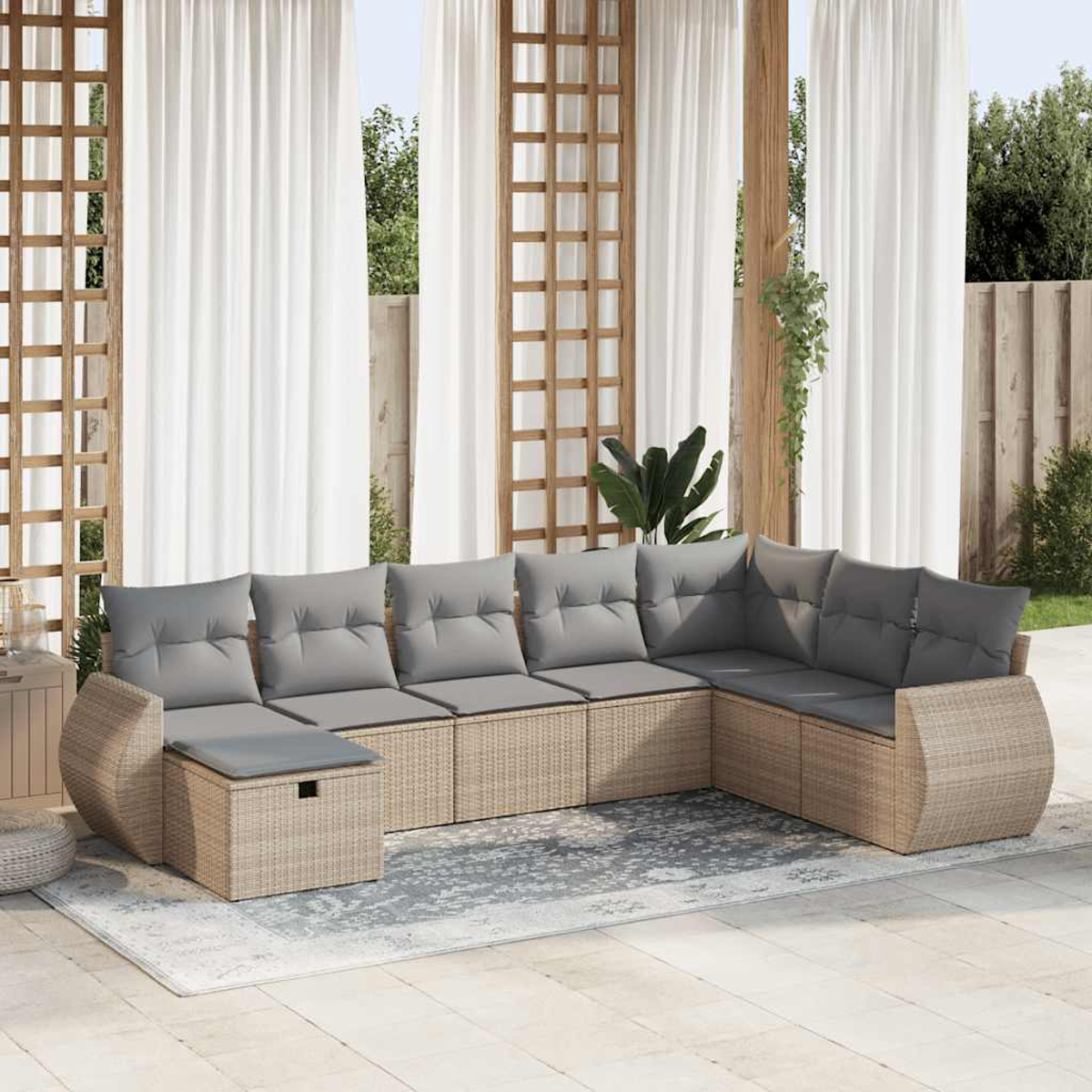 Divano componibile in rattan beige con cuscini grigi su un patio, con tende bianche e struttura in legno.