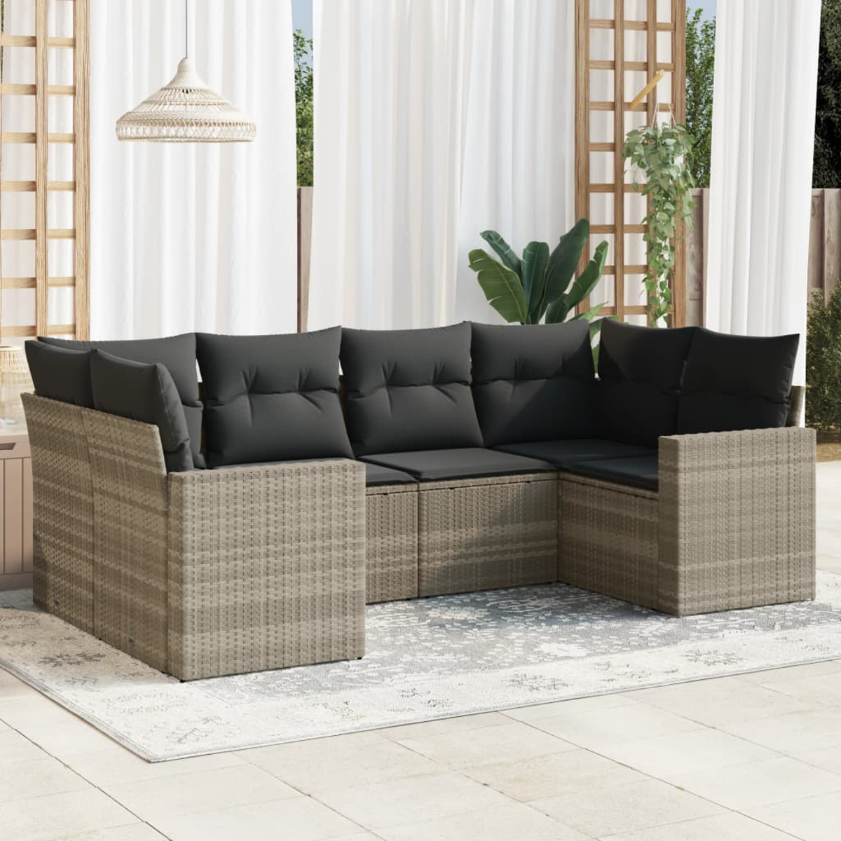 Beiges Outdoor-Ecksofa aus Korbgeflecht mit grauen Kissen auf einem Teppich, nahe Vorhängen und Pflanzen.