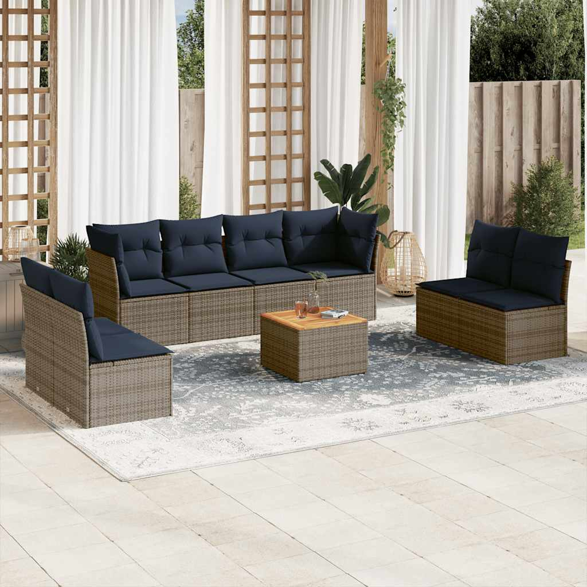Korbmöbel-Set mit marineblauen Kissen, Tisch und Teppich auf Terrasse.