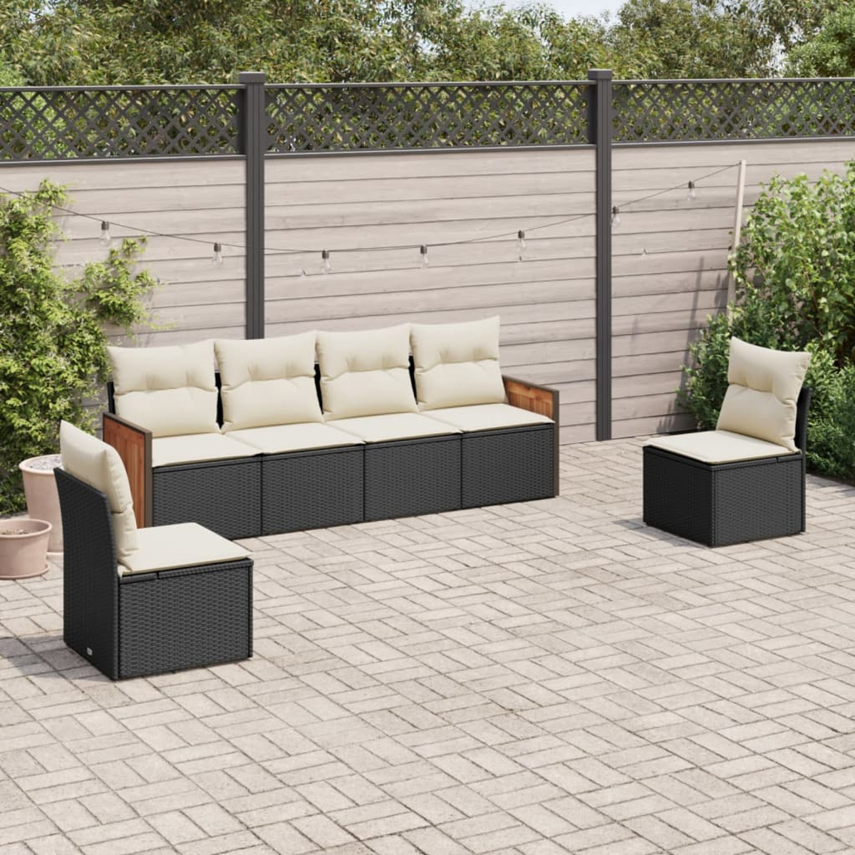 Gartenmöbel-Set auf der Terrasse. Beinhaltet Sofa, Stühle und Kissen. Holzakzente und Zäune.