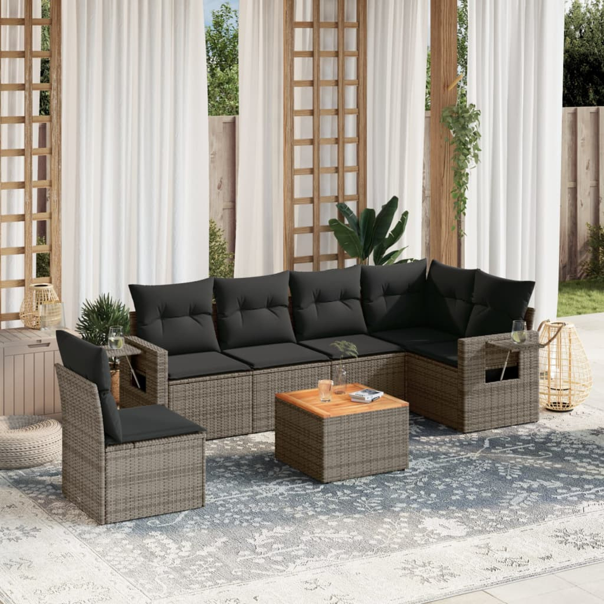 Graues Korbmöbel-Set für den Außenbereich mit schwarzen Kissen auf Teppich. Beinhaltet Sofa, Stühle, Tisch.
