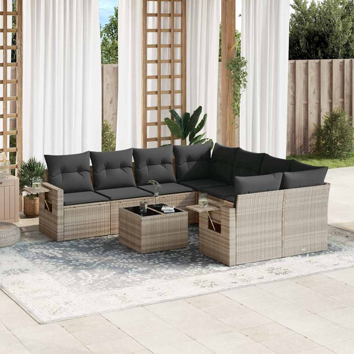 Geflochtenes Outdoor-Ecksofa mit grauen Kissen, einem Tisch und weißen Vorhängen im Hintergrund.