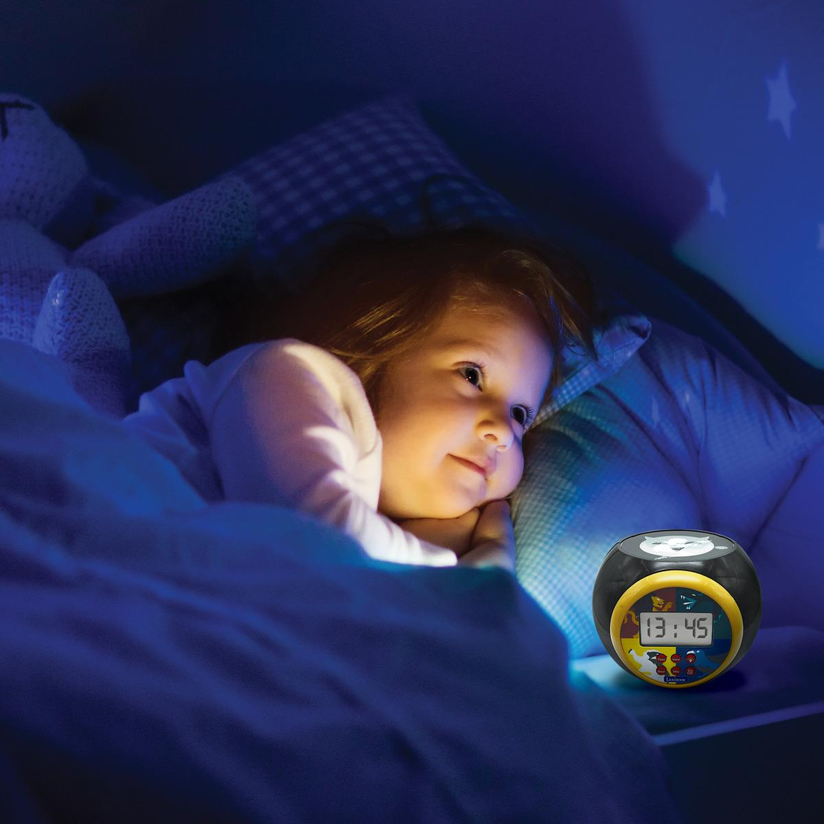 Un bambino piccolo è a letto e guarda una sveglia nera a forma di gufo, che mostra le 13:45.