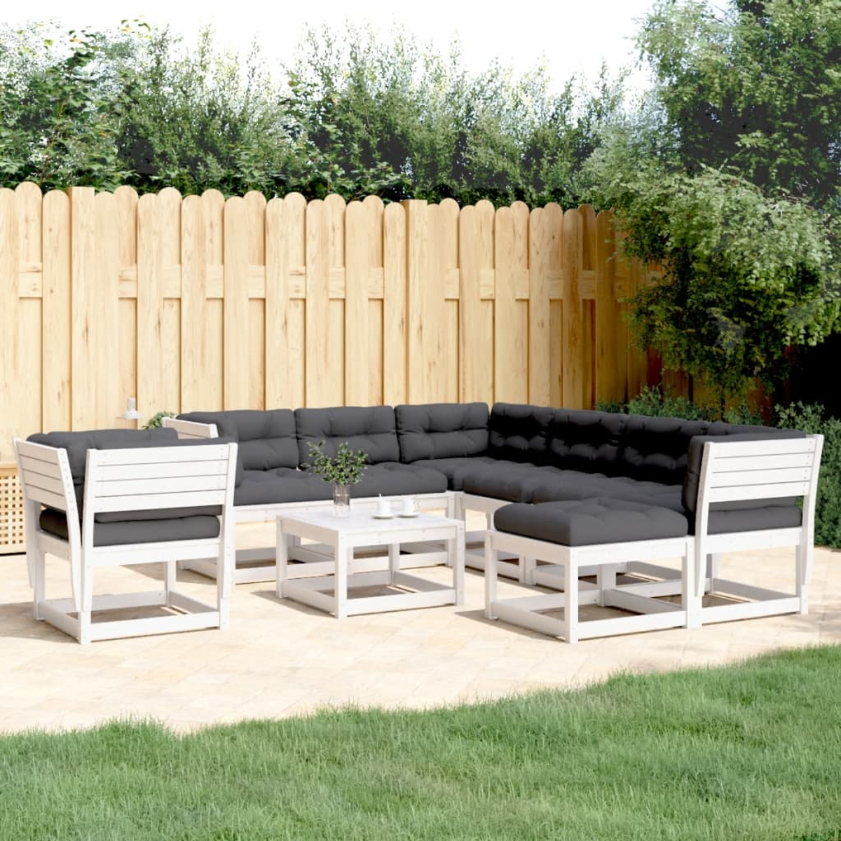 Weißes Rattan-Sofa-Set im Freien mit grauen Kissen auf Gras.
