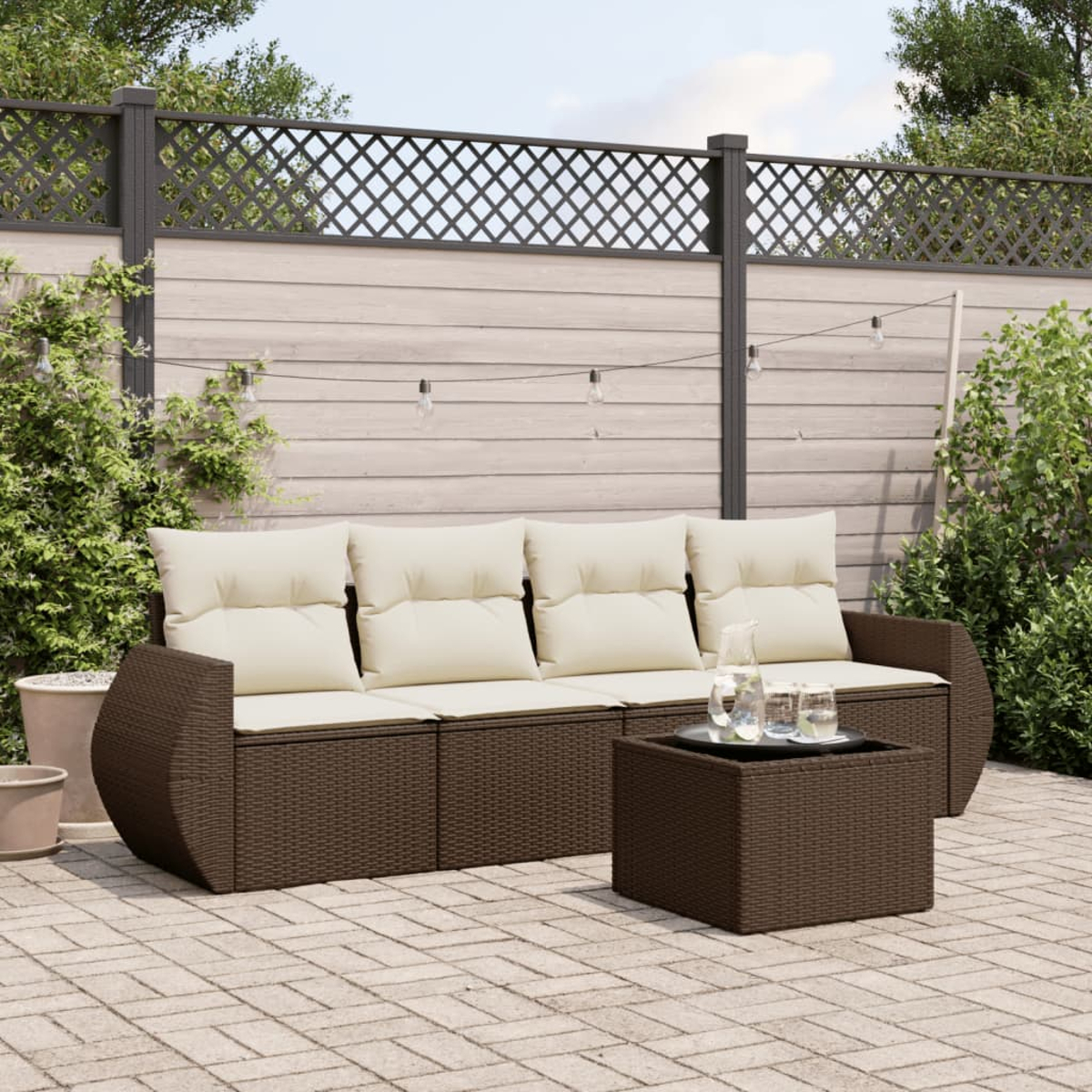 Set divano in rattan marrone con cuscini bianchi e un tavolo su un patio.