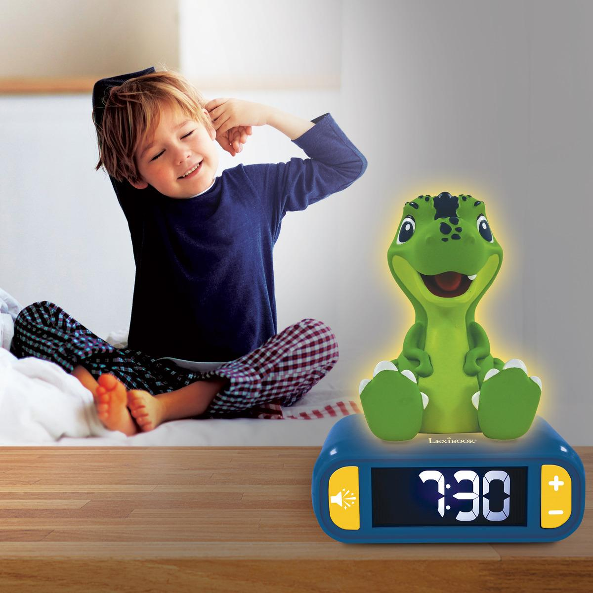 Niño en pijama sentado en la cama junto a un despertador de dinosaurio verde, sonriendo. 7:30.