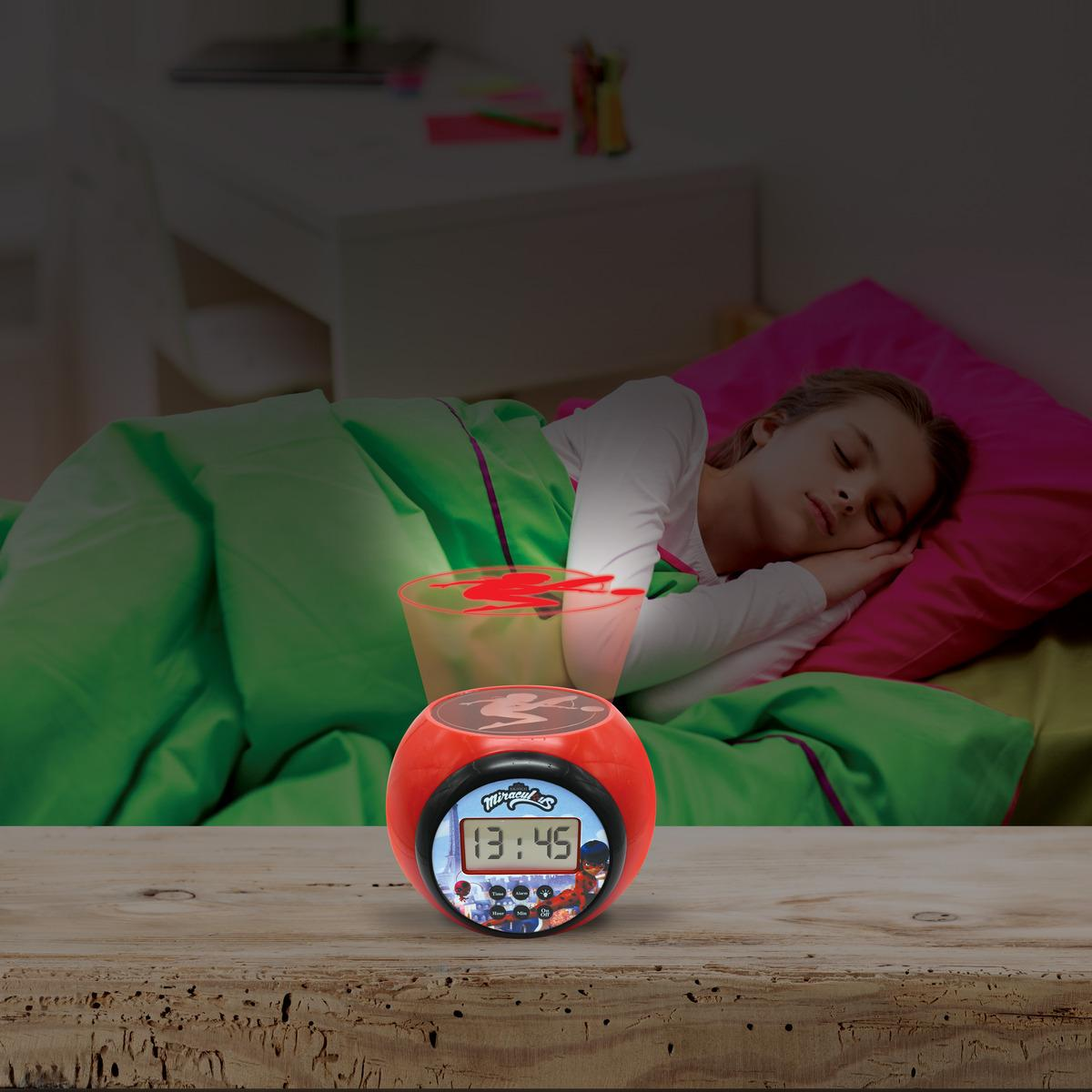 Niña durmiendo en una cama, despertador Miraculous mostrando 13:45, proyectando un diseño en el techo.
