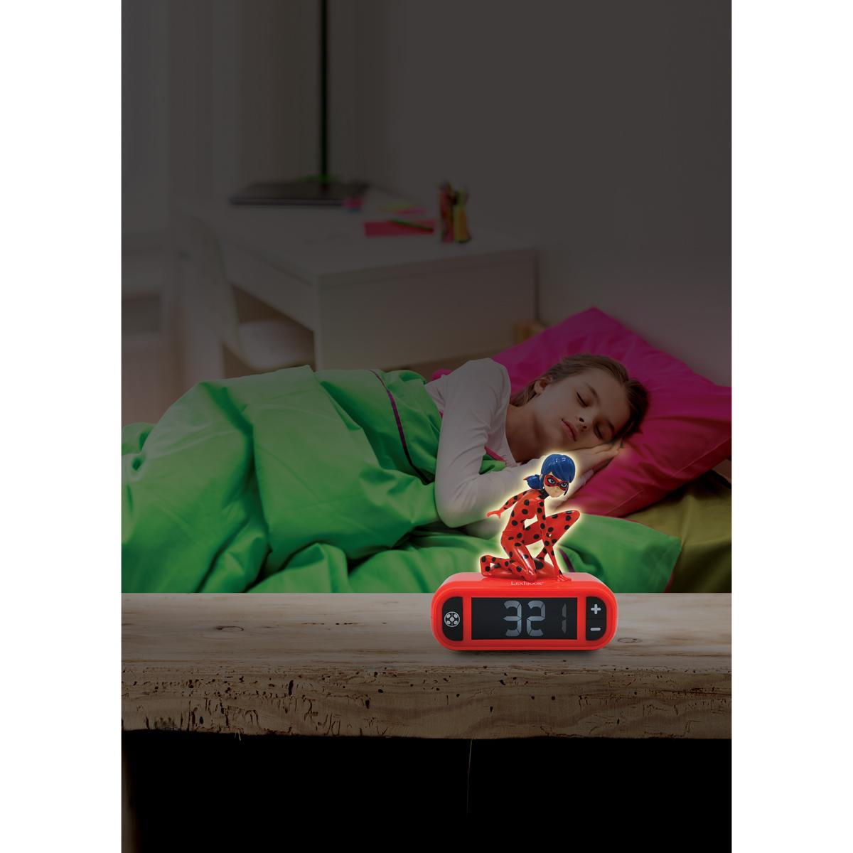 Niña dormida con despertador de Ladybug en una mesa de madera.