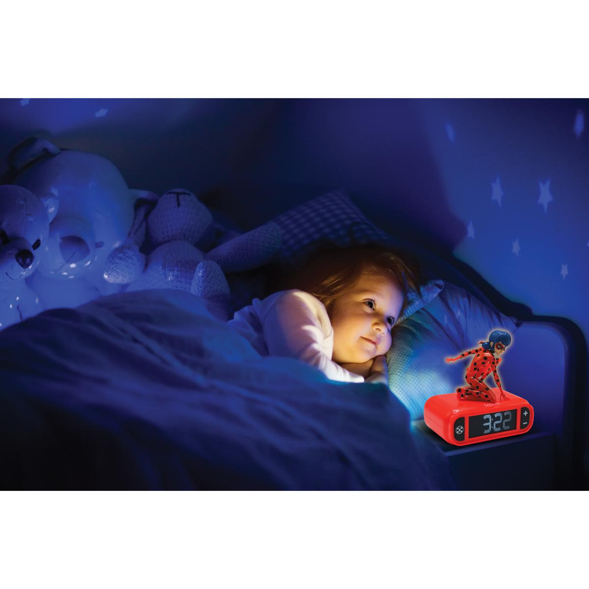 Una niña en la cama, mirando un despertador rojo con una figura de Ladybug. La hora es 3:22.