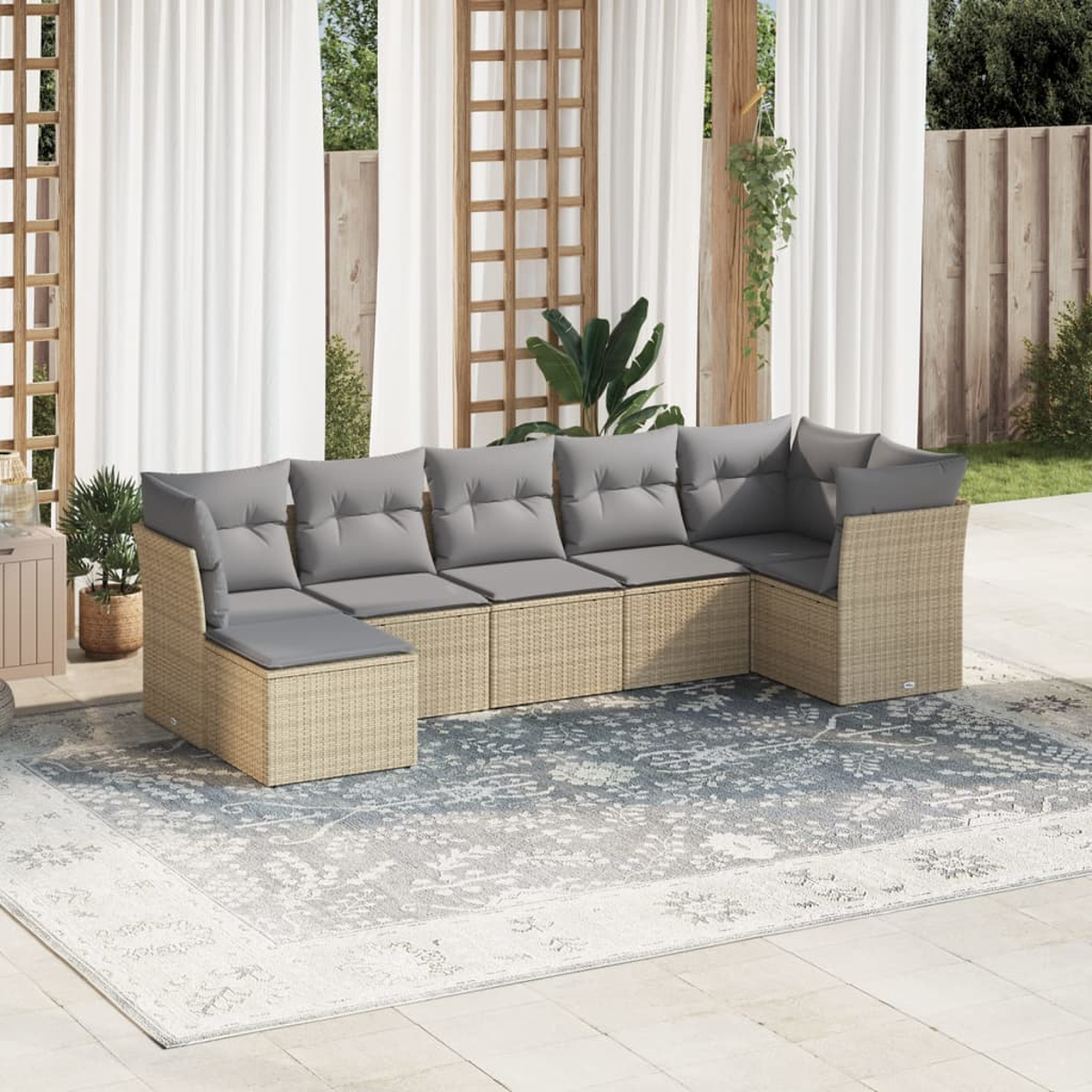 Beiges Ecksofa aus Rattan mit grauen Kissen auf einem hellblauen und weißen Teppich. Draußen, mit Vorhängen.