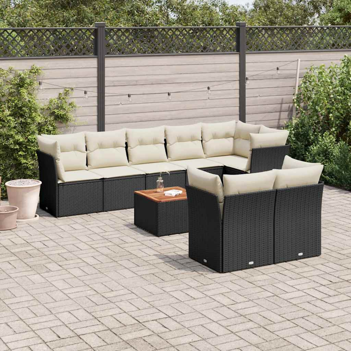Outdoor-Sitzgruppe mit schwarzem Korbgeflecht, beigen Kissen, auf einer Ziegelterrasse. Kaffeetisch inklusive.