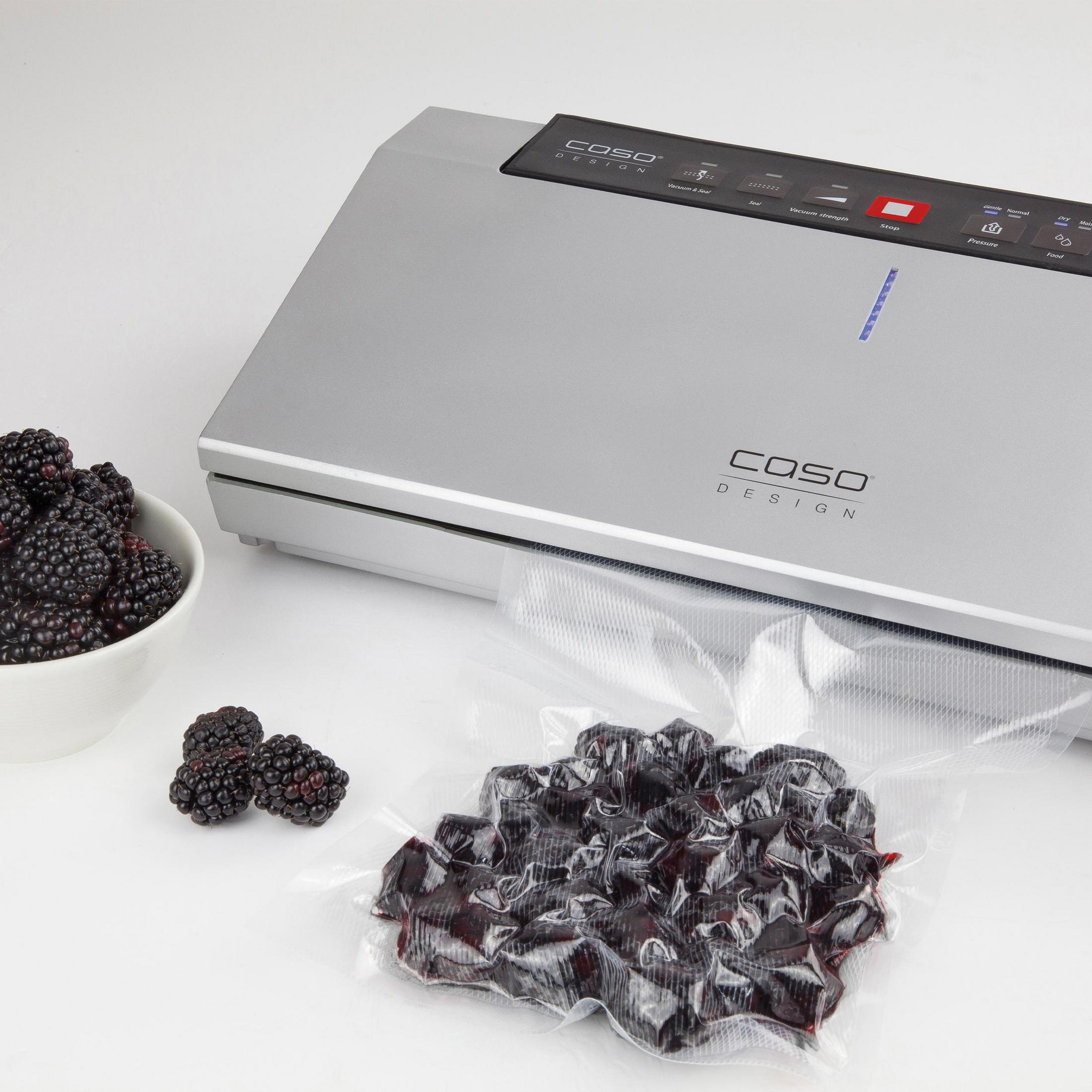 Vakuumiergerät mit Brombeeren in einer Schüssel und in einem versiegelten Beutel, weißer Hintergrund.