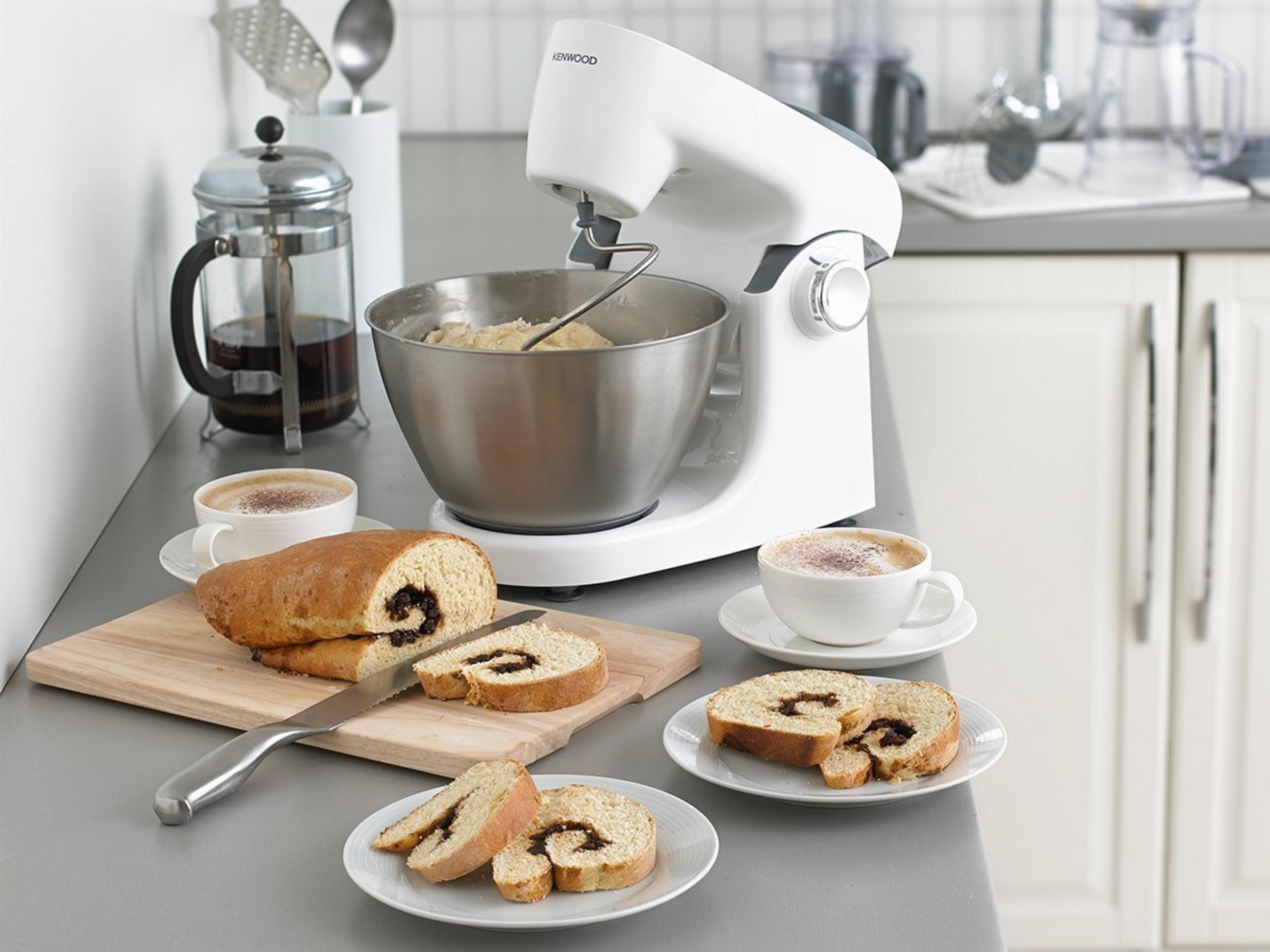 Scena cucina con impastatrice Kenwood, pane e caffè sul bancone.