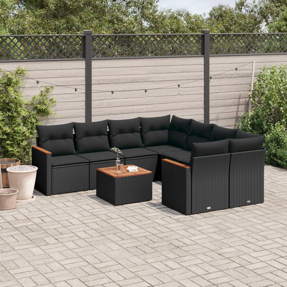 Gartenmöbel-Set auf einer Terrasse. Enthält einen Tisch und schwarz gepolsterte Sitzgelegenheiten.