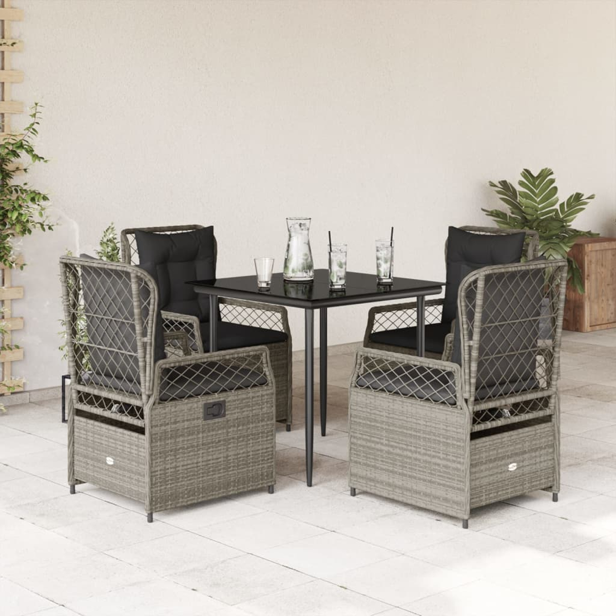 Terrassenset mit grauen Rattan-Stühlen, schwarzem Tisch mit Getränken und weißer Wand im Hintergrund.