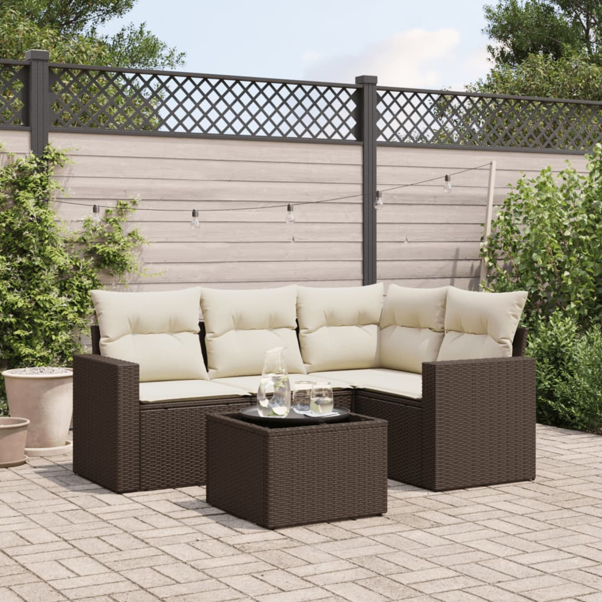 Braunes geflochtenes Outdoor-Sofaset mit cremefarbenen Kissen und quadratischem Couchtisch. Pflasterterrassen.