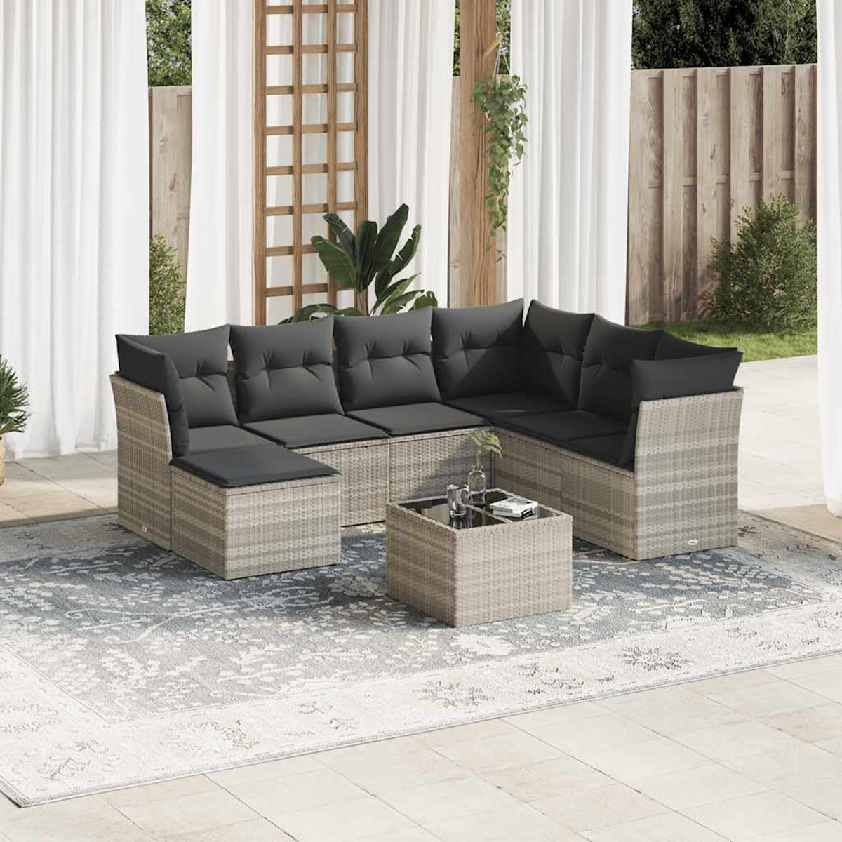 Graues Rattan-Ecksofa-Set mit Couchtisch, auf einem Teppich, im Freien.