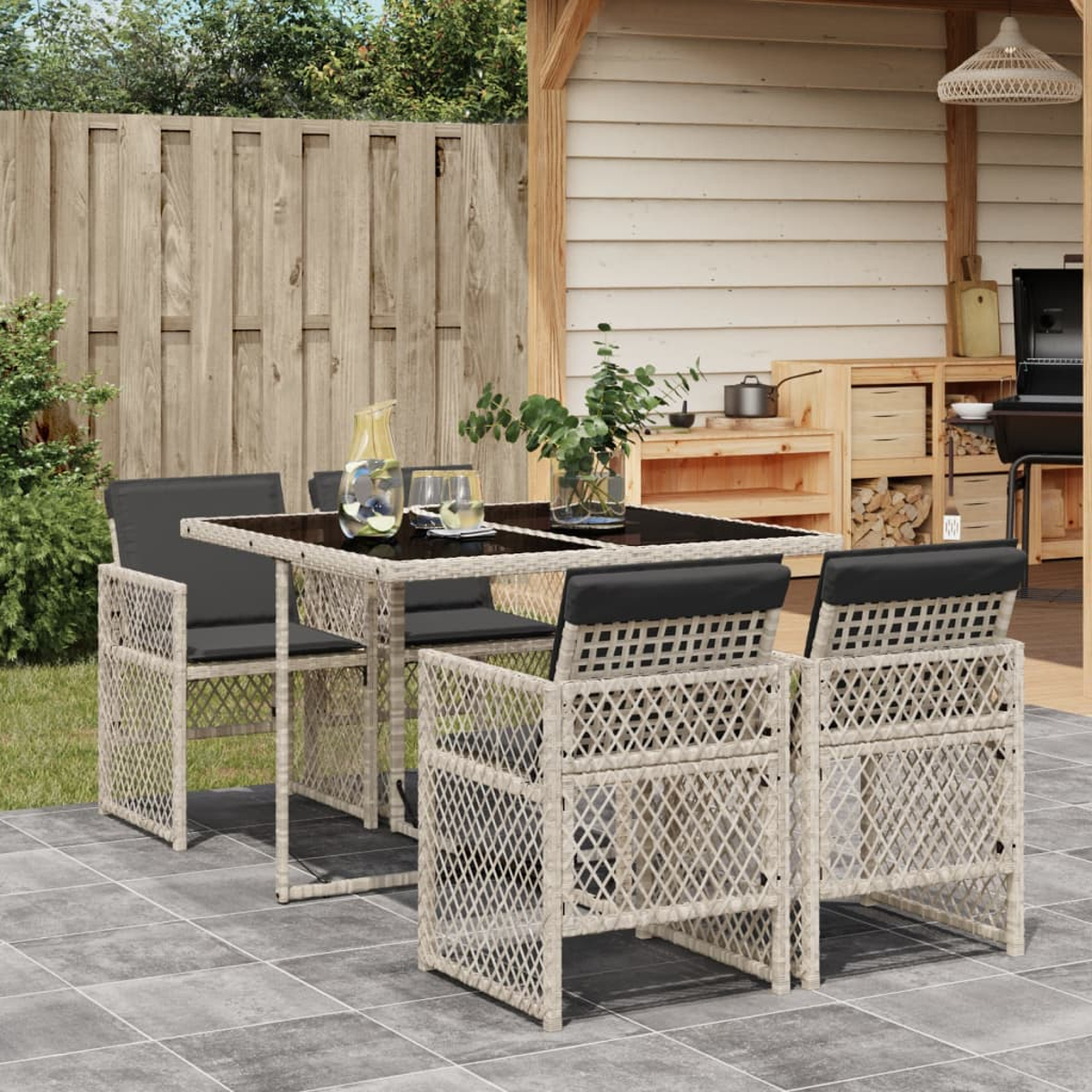 Essgruppe im Freien mit Tisch und Stühlen. Tisch hat schwarze Platte, Stühle schwarze Kissen.