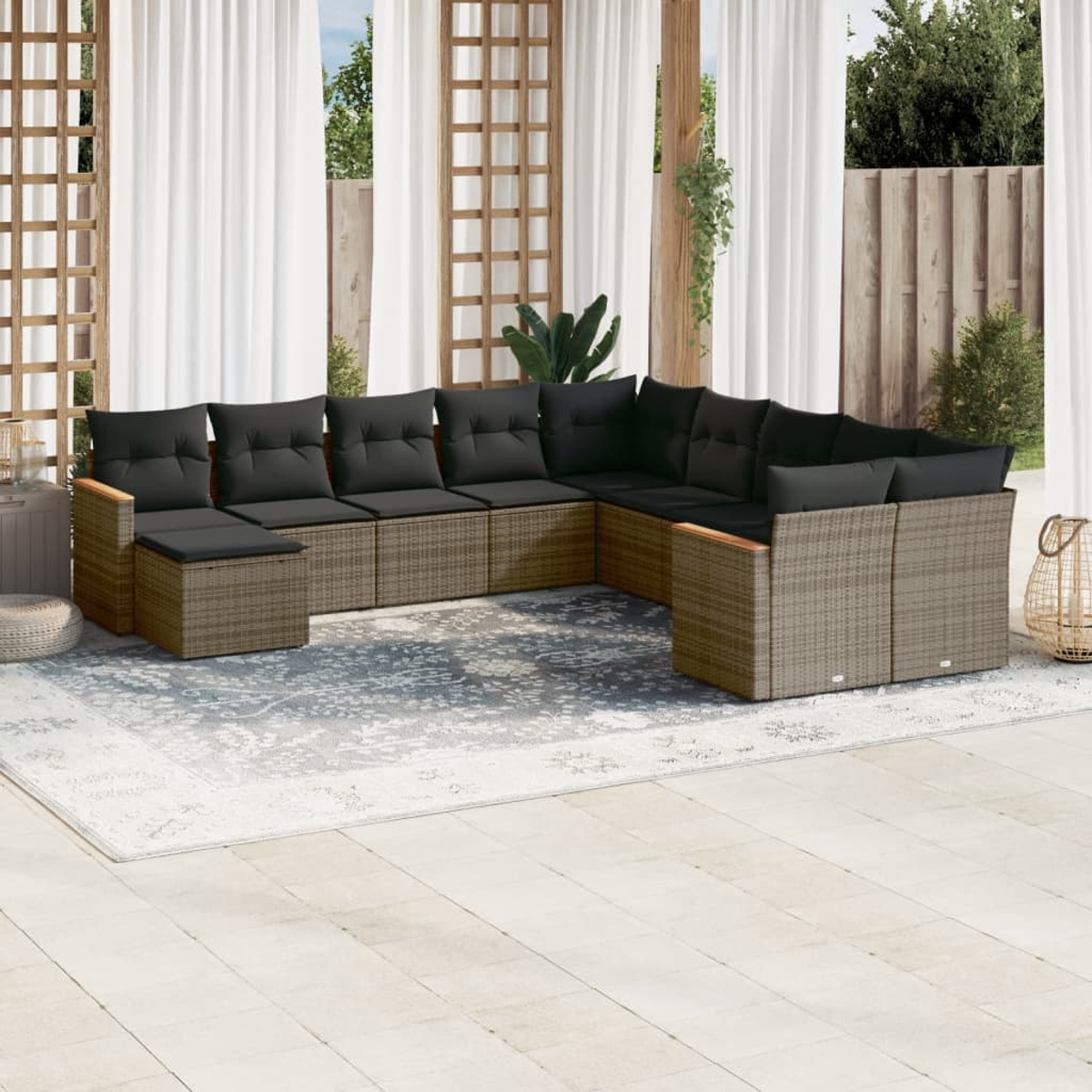 Outdoor-Rattansofa-Set mit schwarzen Kissen auf einem gemusterten Teppich.