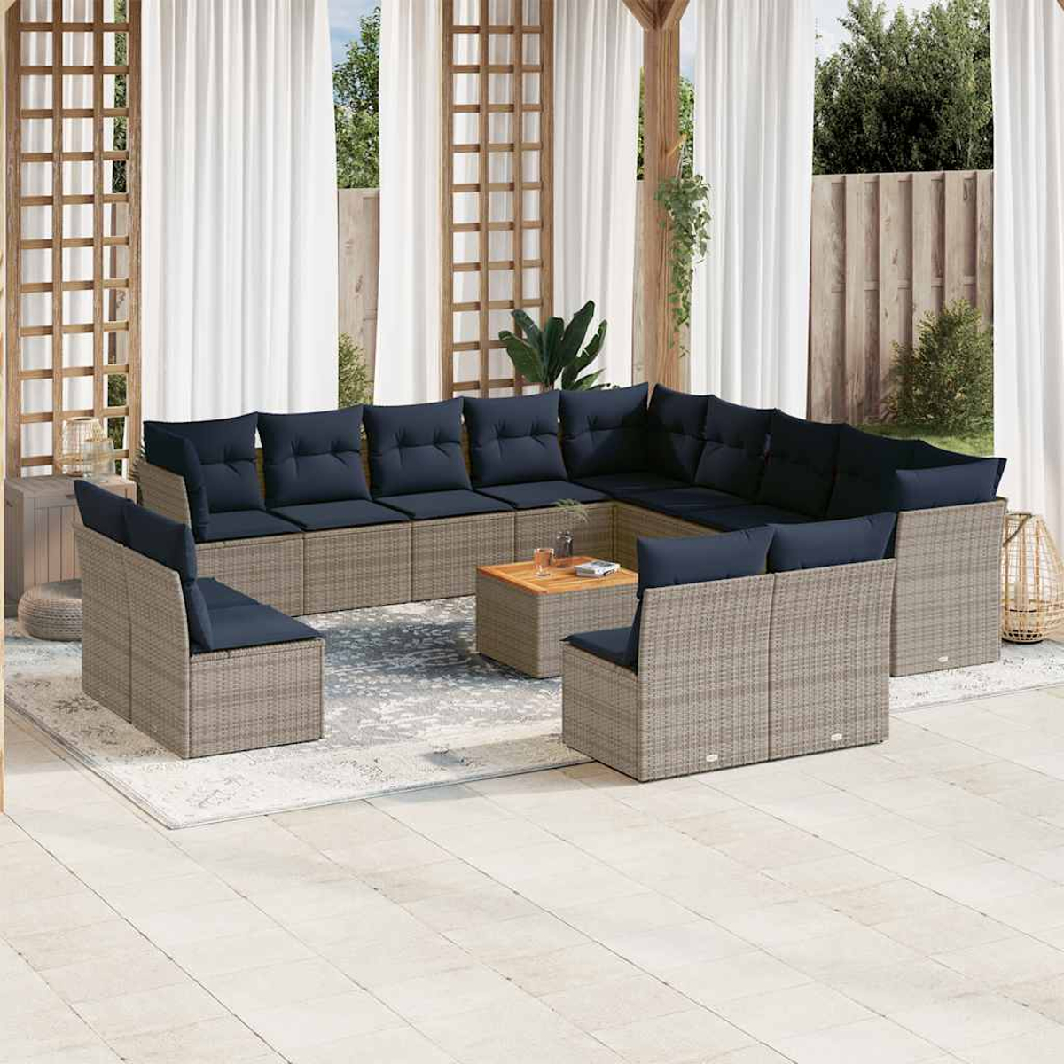 Set divano angolare da esterno. Vimini grigio, cuscini blu, tavolo e ambiente esterno.