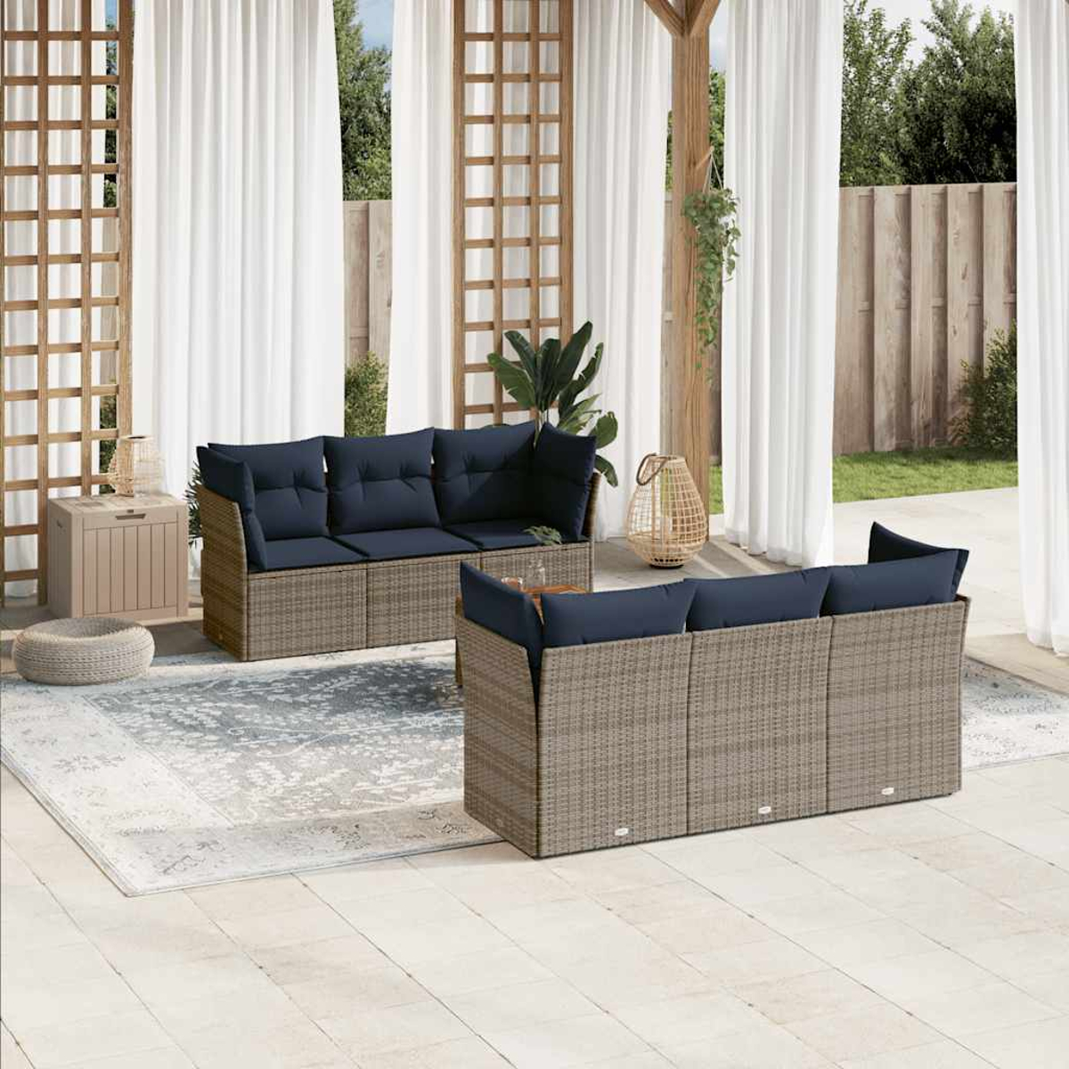 Divano componibile in rattan da esterno con cuscini blu, su un patio. Tende sullo sfondo.