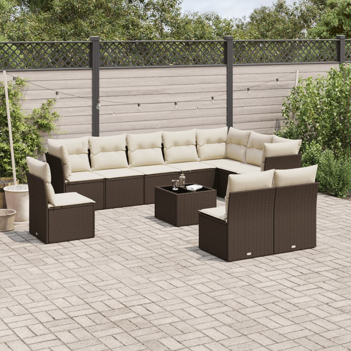 Un set di mobili da esterno in vimini marrone con cuscini color crema, tra cui un divano angolare e sedie, su un patio.